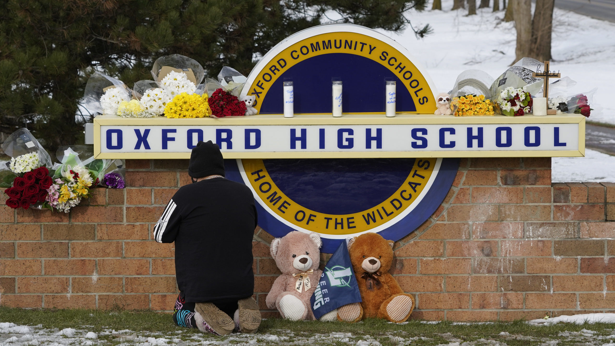 A well wisher kneels to pray at a memorial on the sign of Oxford High School in Oxford, Mich., Wedn...