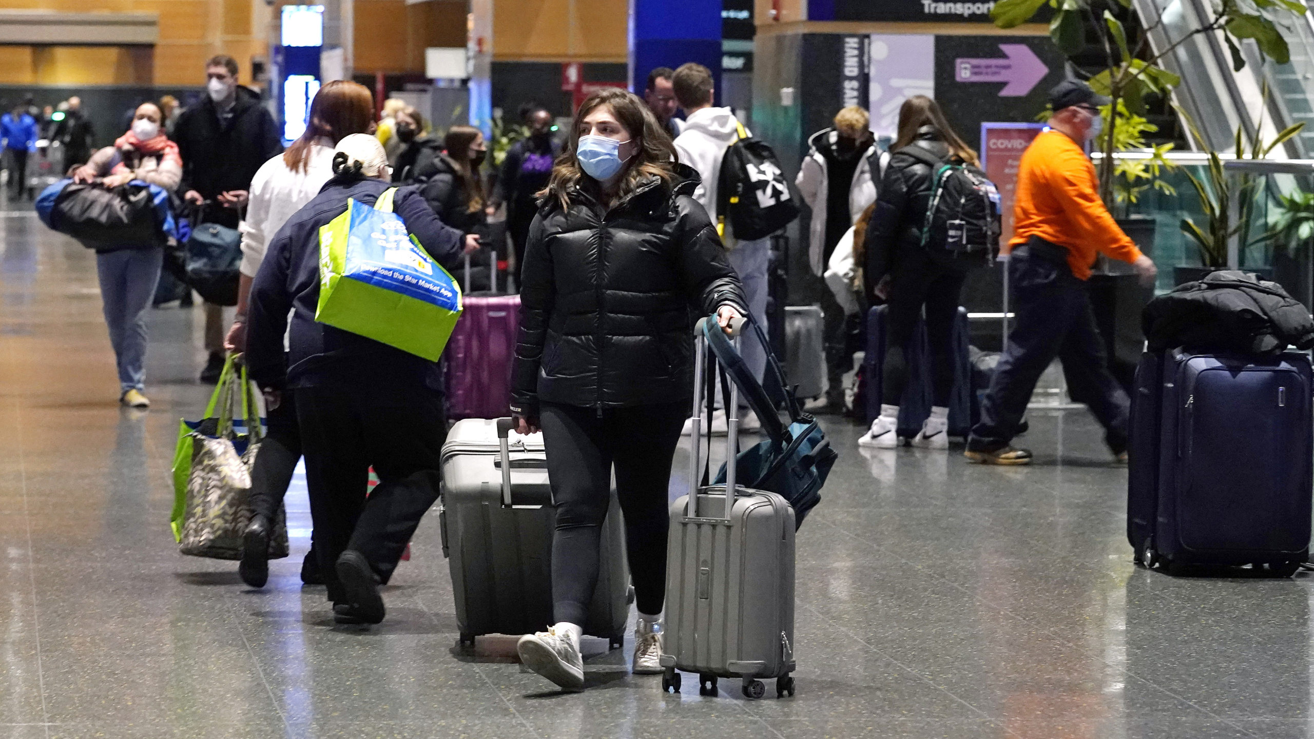 Travelers trek through Terminal E at Logan Airport, Tuesday, Dec. 21, 2021, in Boston.  At least th...