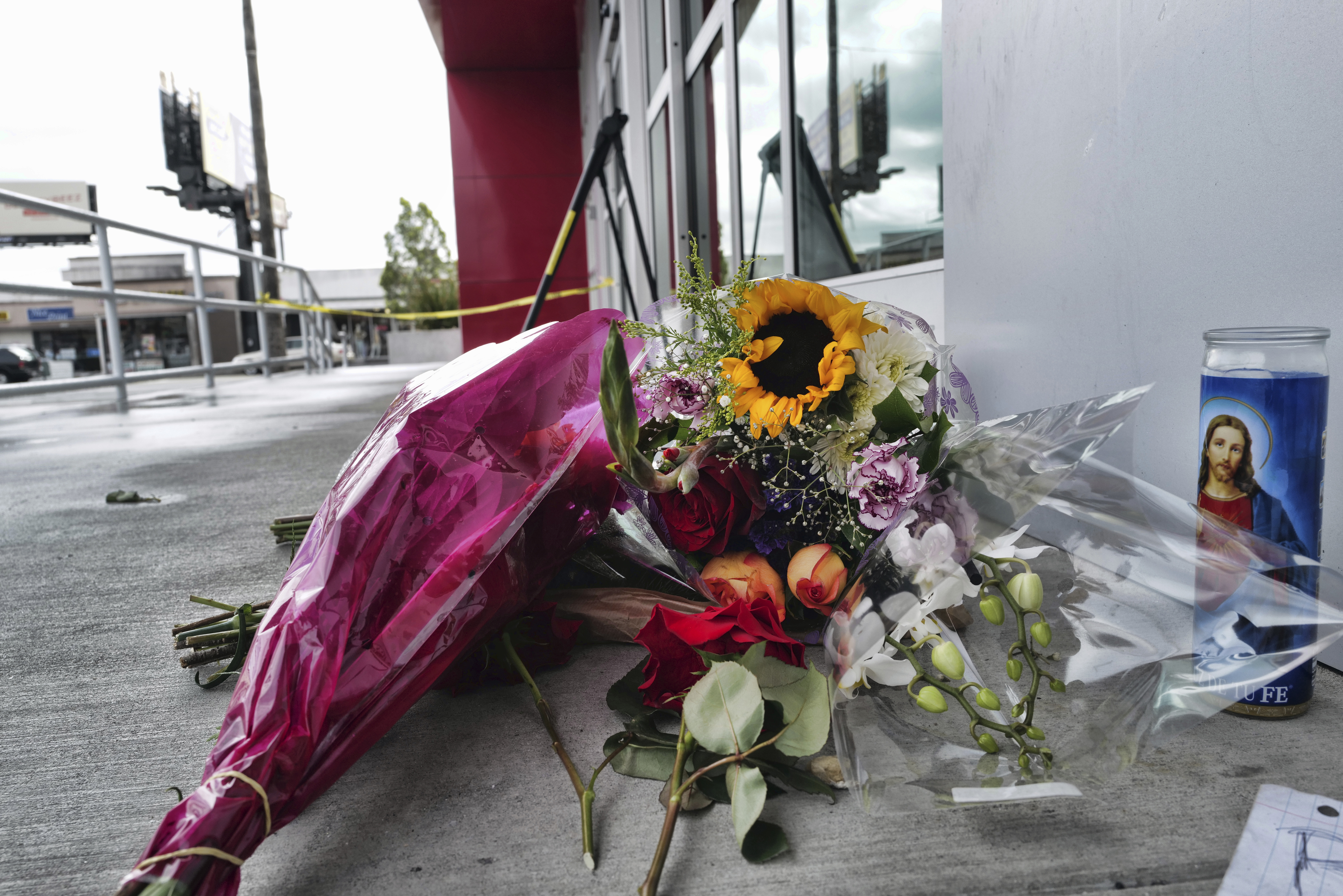 A votive candle and flowers are left for a teen who was fatally shot at a department store in the N...