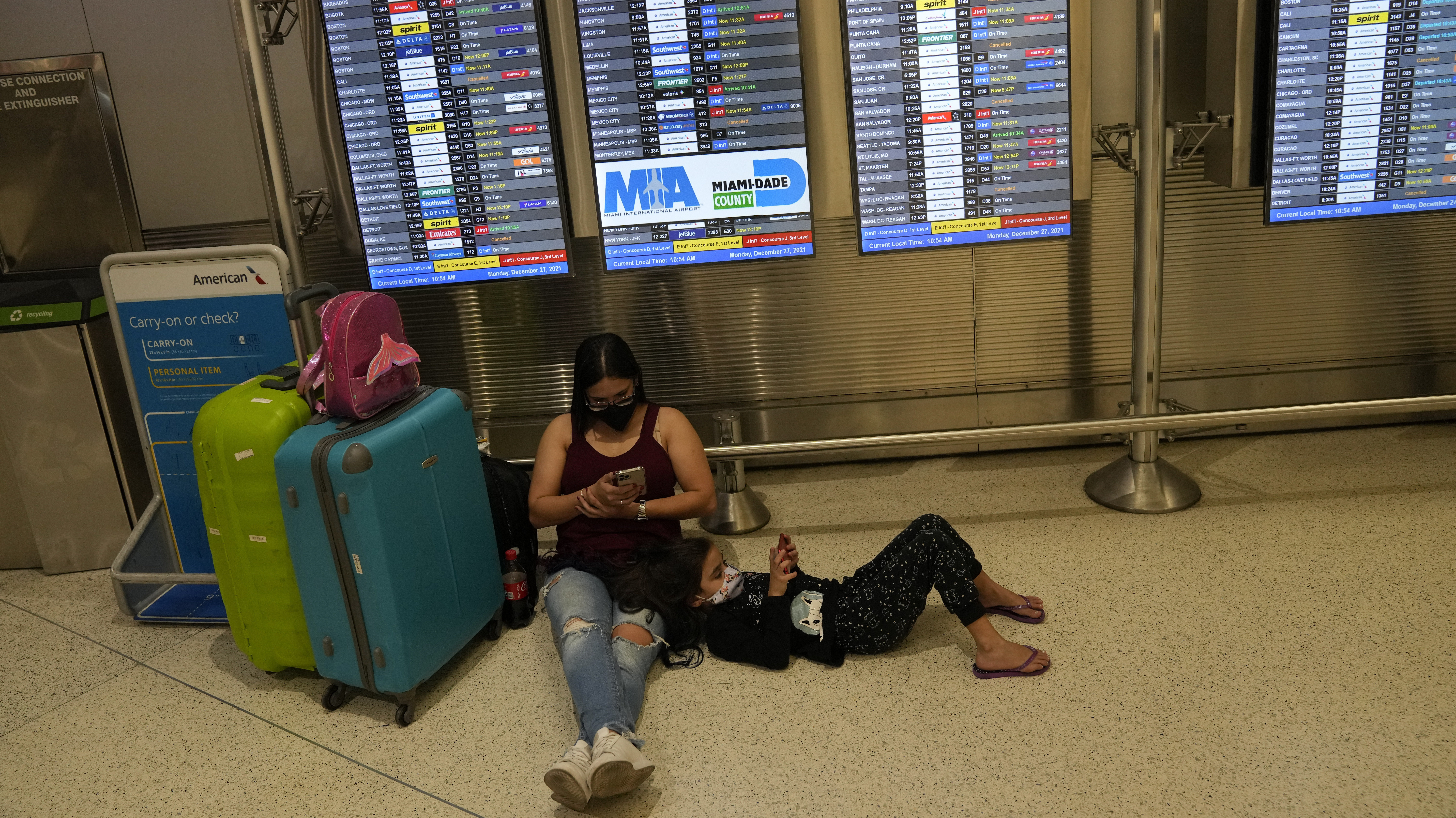 FILE: A woman and child from Brazil wait for their flight underneath a board showing roughly a doze...