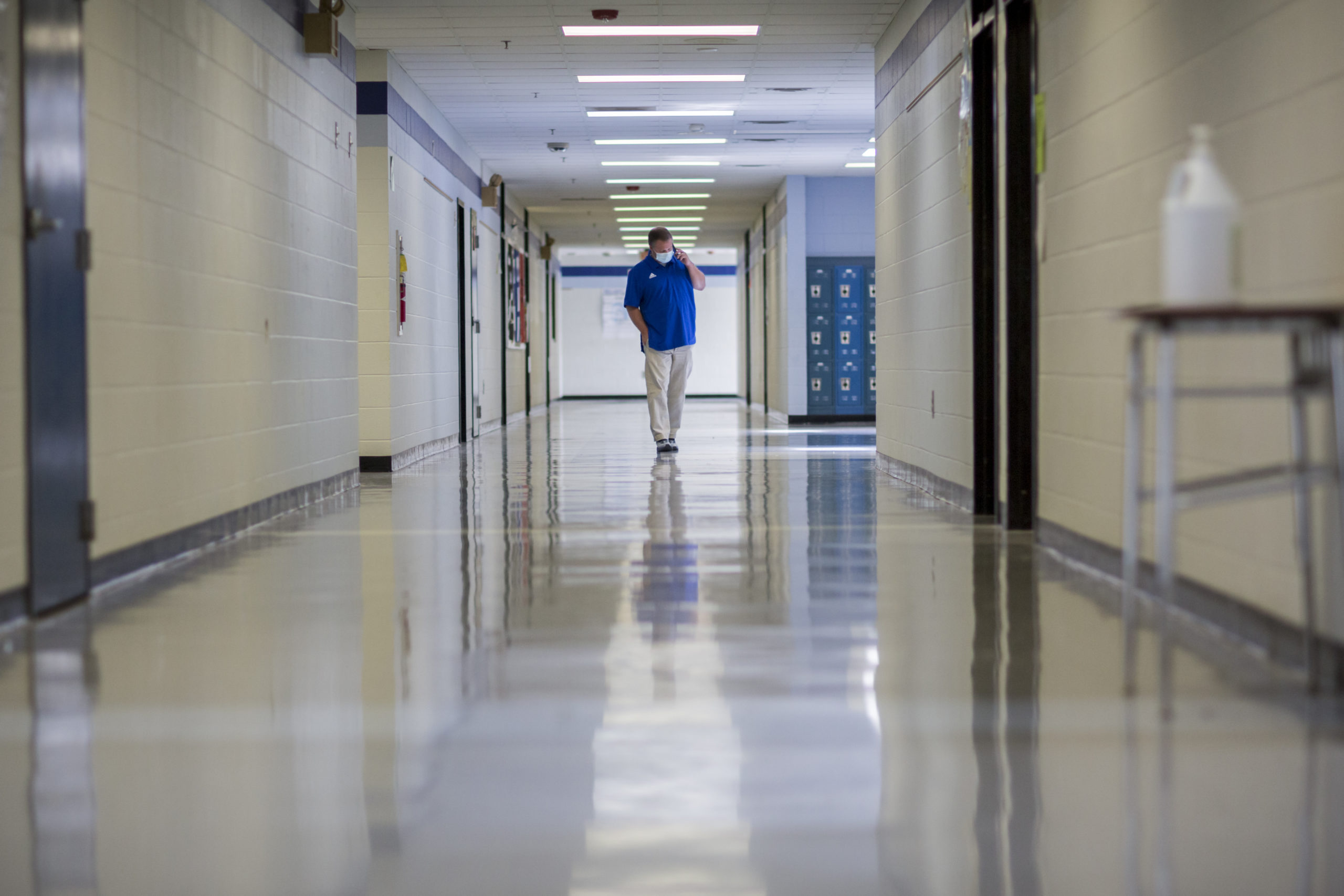 FILE - A middle school principal walks the empty halls of his school as he speaks with one of his t...