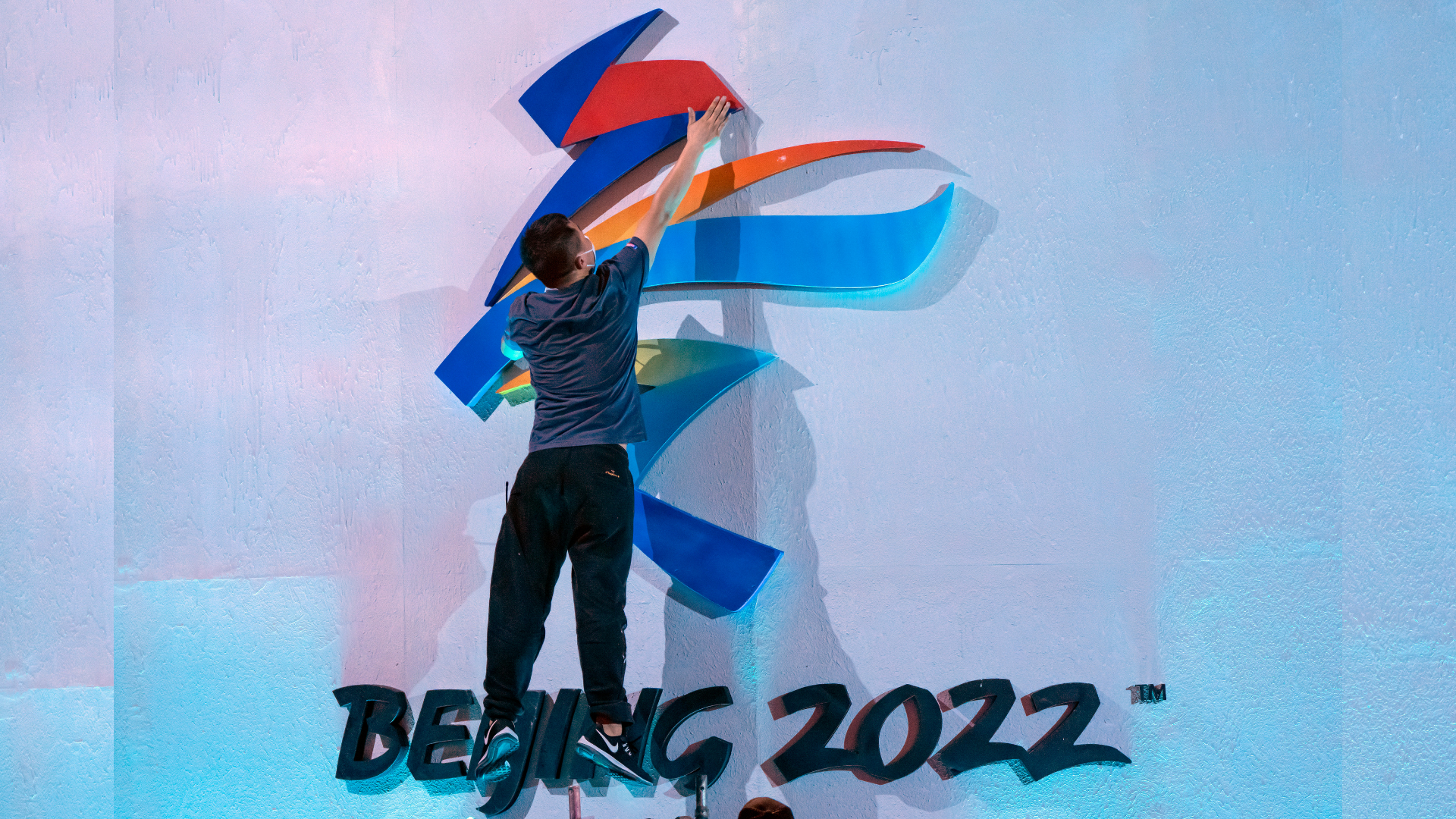 A crew member leaps to fix a logo for the 2022 Beijing Winter Olympics before a launch ceremony to ...
