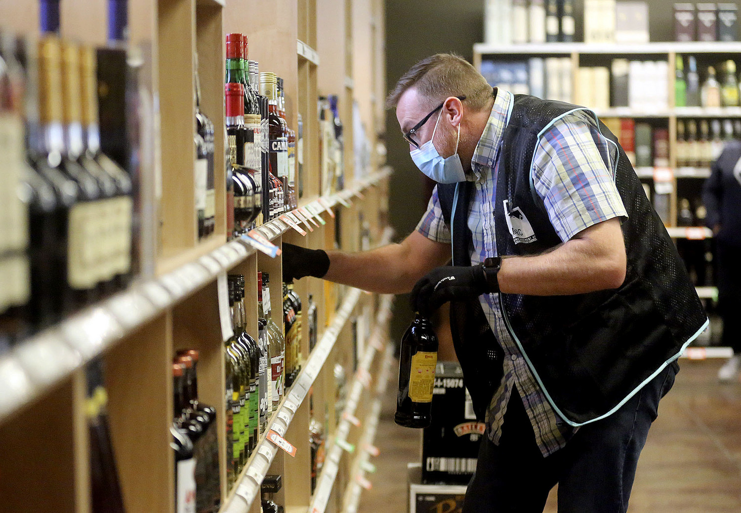 Justin Robertson, a full-time staffer, stocks the shelves at a state liquor store in Salt Lake City...