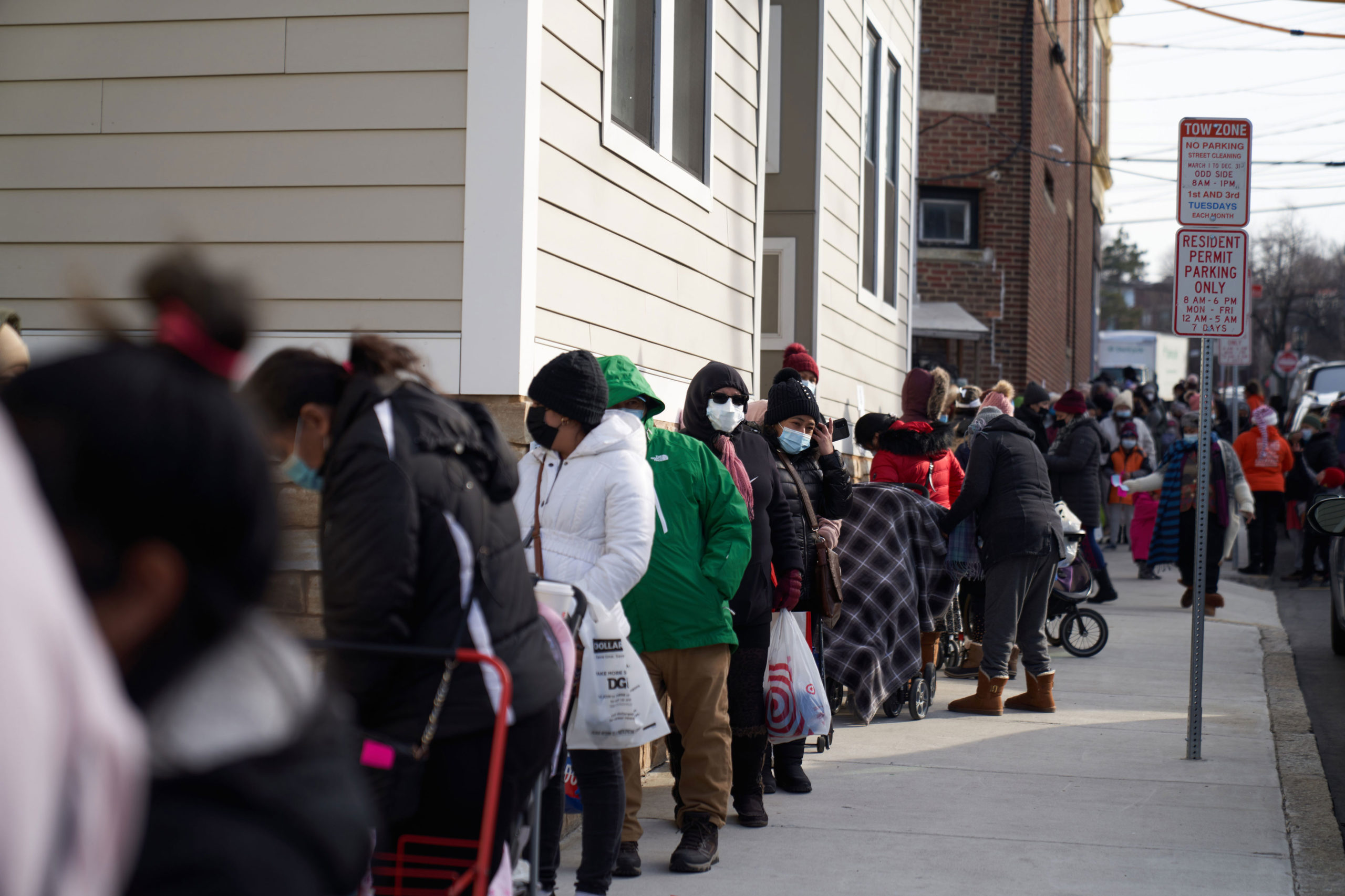 Residents wait in line to receive free Covid-19 at-home test kits with groceries at a food distribu...