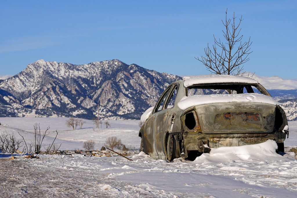 Snow covers the burned remains of a car after wildfires ravaged the area Sunday, Jan. 2, 2022, in S...