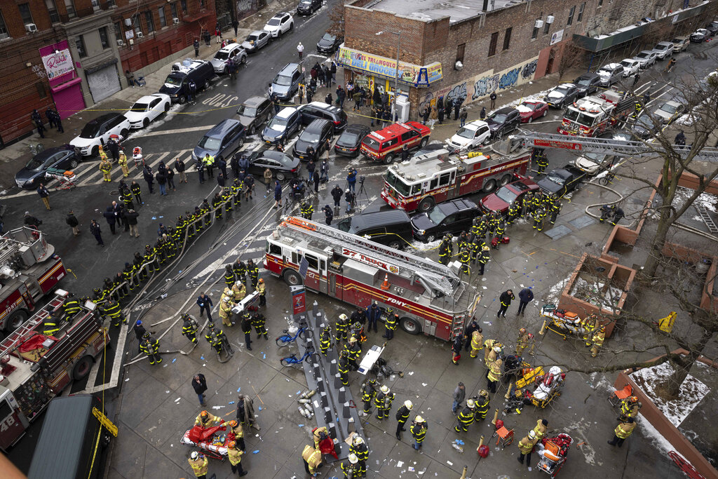 Firefighters work outside an apartment building after a fire in the Bronx, Sunday, Jan. 9, 2022, in...