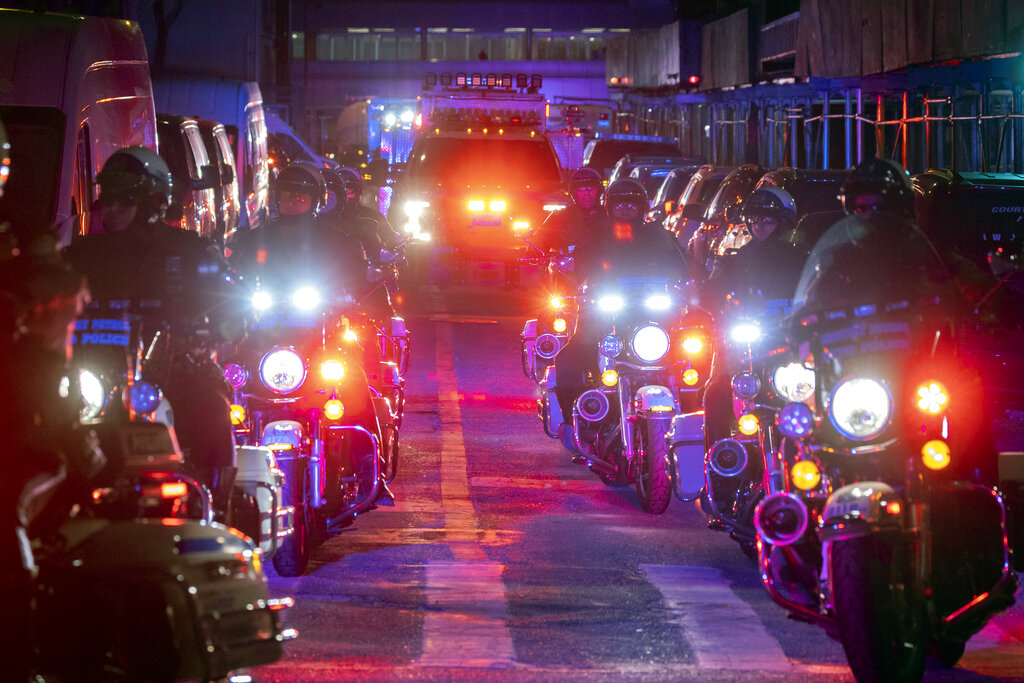 NYPD officers in motorcycles lead an ambulance carrying Officer Wilbert Mora as he is transferred f...