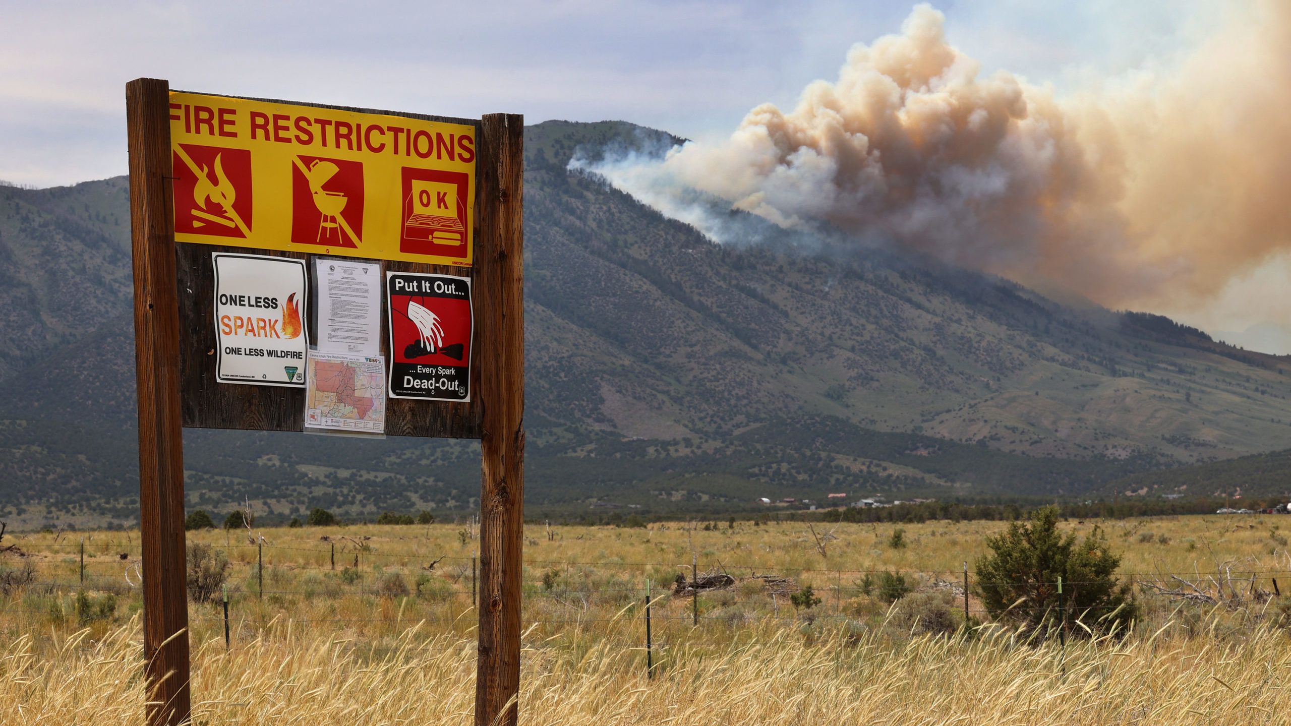 FILE: A fire restriction sign sits along the road in Rush Valley as a wildfire burns on Victory Mou...
