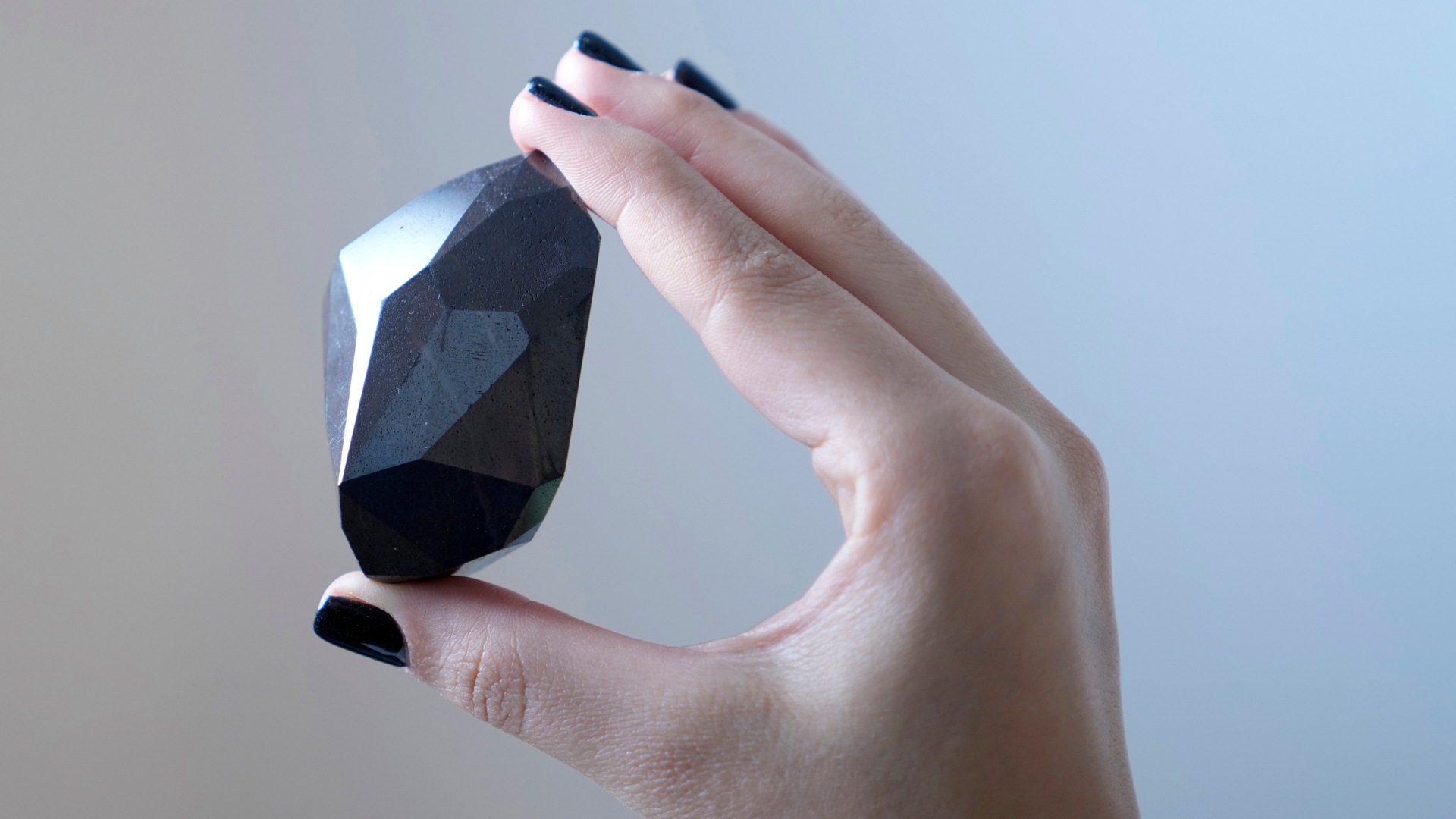 An employee of Sotheby's Dubai presents a 555.55 Carat Black Diamond "The Enigma" to be auctioned a...
