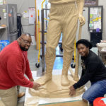 Green Flake's descendants Kellen Perkins (left) and Tamu Smith (right) contribute to molding the base of the Green Flake statue that will become part of the Black pioneer monument being erected at This is the Place Heritage Park. Photo Credit: Mauli Bonner