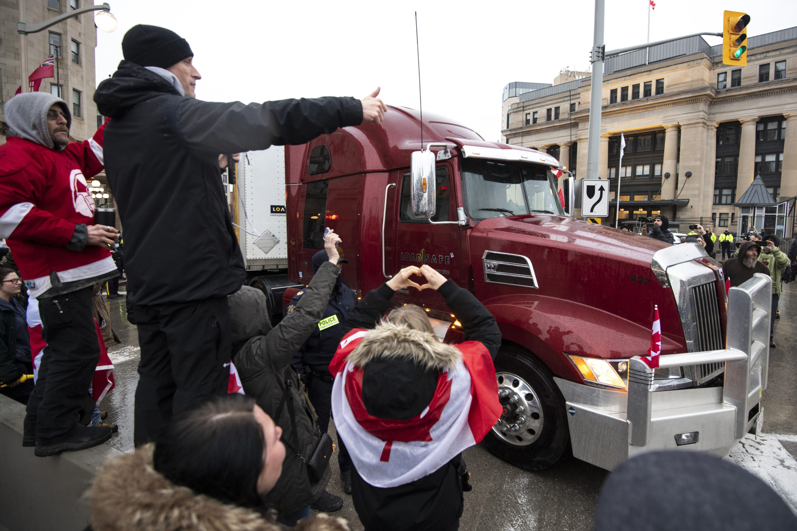 People gesture signs of support towards the driver of a semi-trailer truck as they leave Rideau Str...