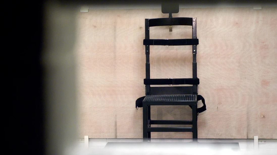 (A firing squad chair in the execution chamber at Utah State Prison is pictured, as seen through th...