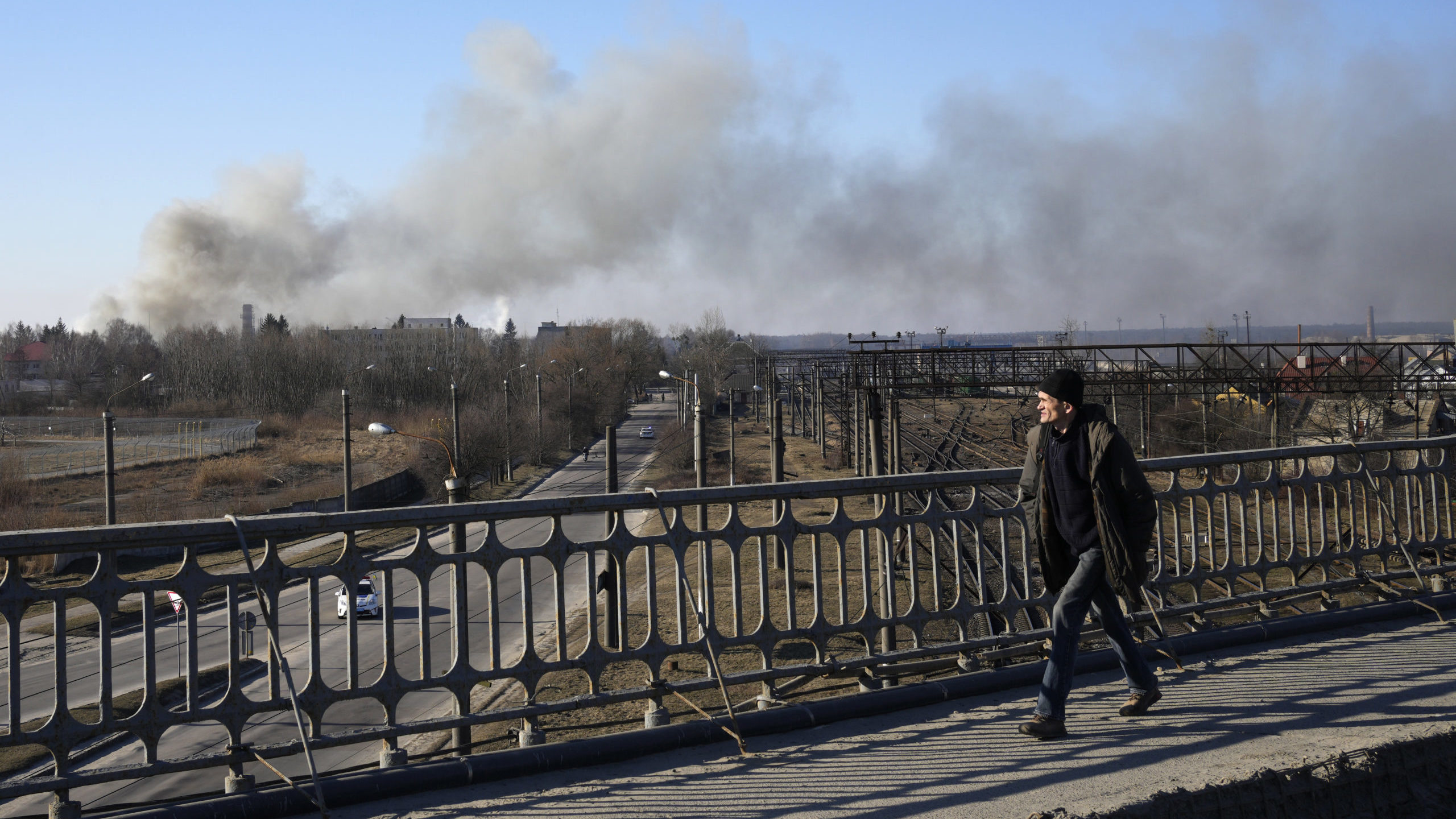 A pedestrian looks at a cloud of smoke raising after an explosion in Lviv, Western Ukraine, Friday,...