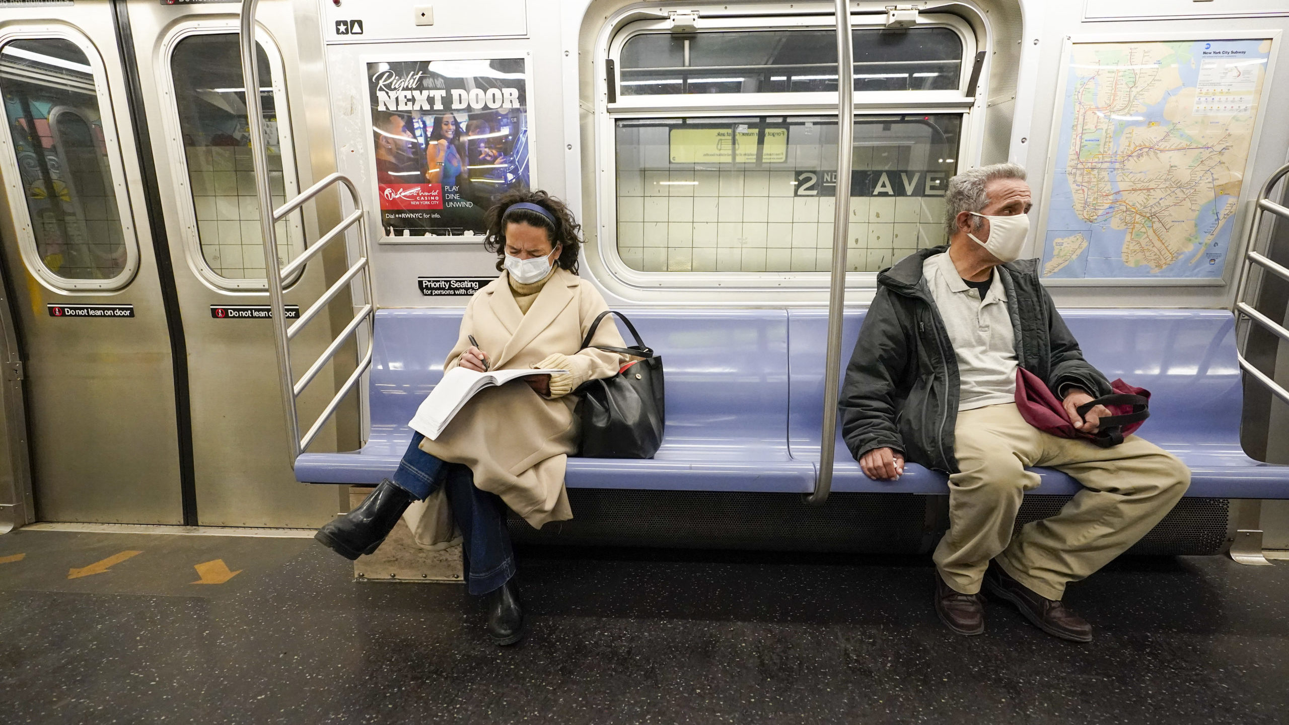 FILE - Commuters wear face masks and social distance while riding an M Train, Tuesday, March 9, 202...