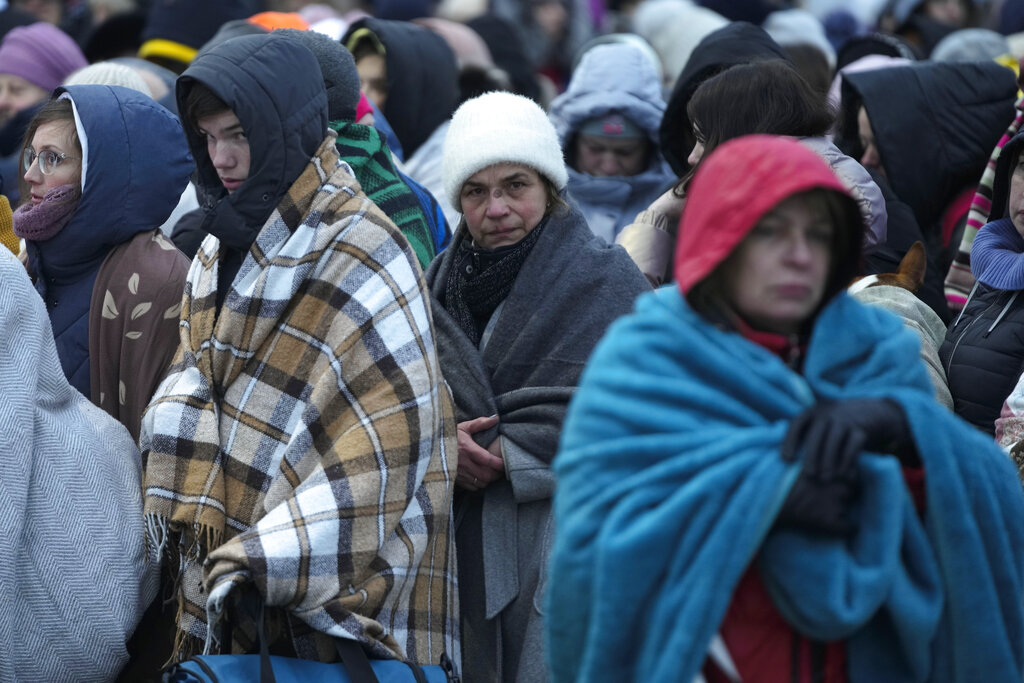 Refugees, mostly women and children, wait in a crowd for transportation after fleeing from the Ukra...