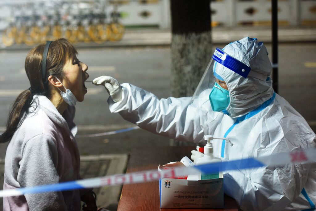 A medical worker takes swab sample from a resident for COVID-19 test in Hangzhou in eastern China's...