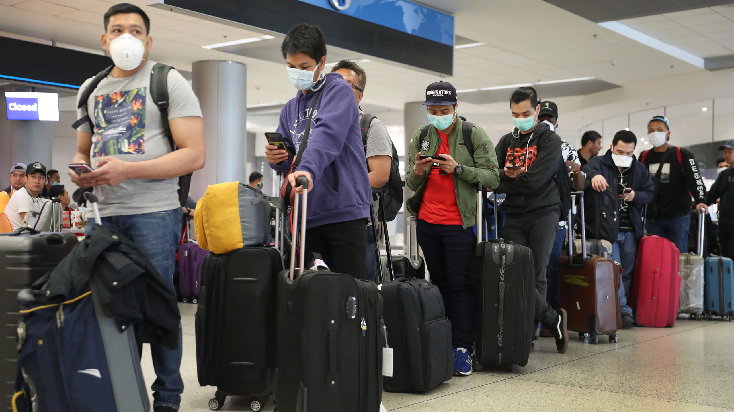 FILE: People wait to check-in at the Qatar Airways counter amid coronavirus fears at Miami Internat...