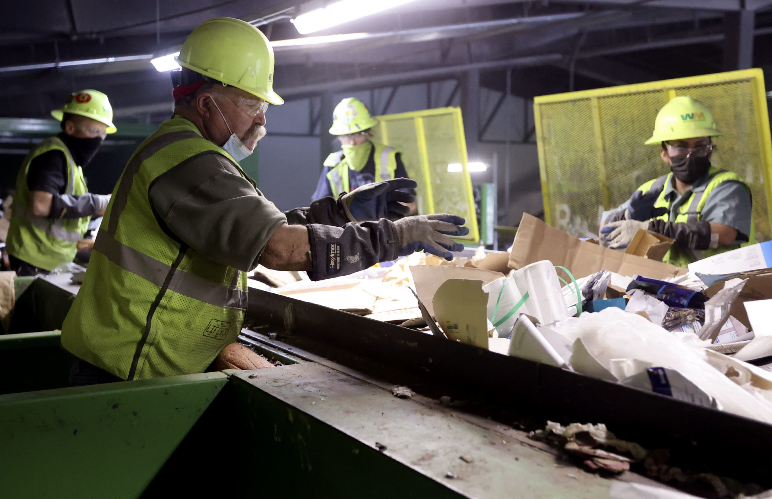 Waste Management workers sorting waste on an assembly line...