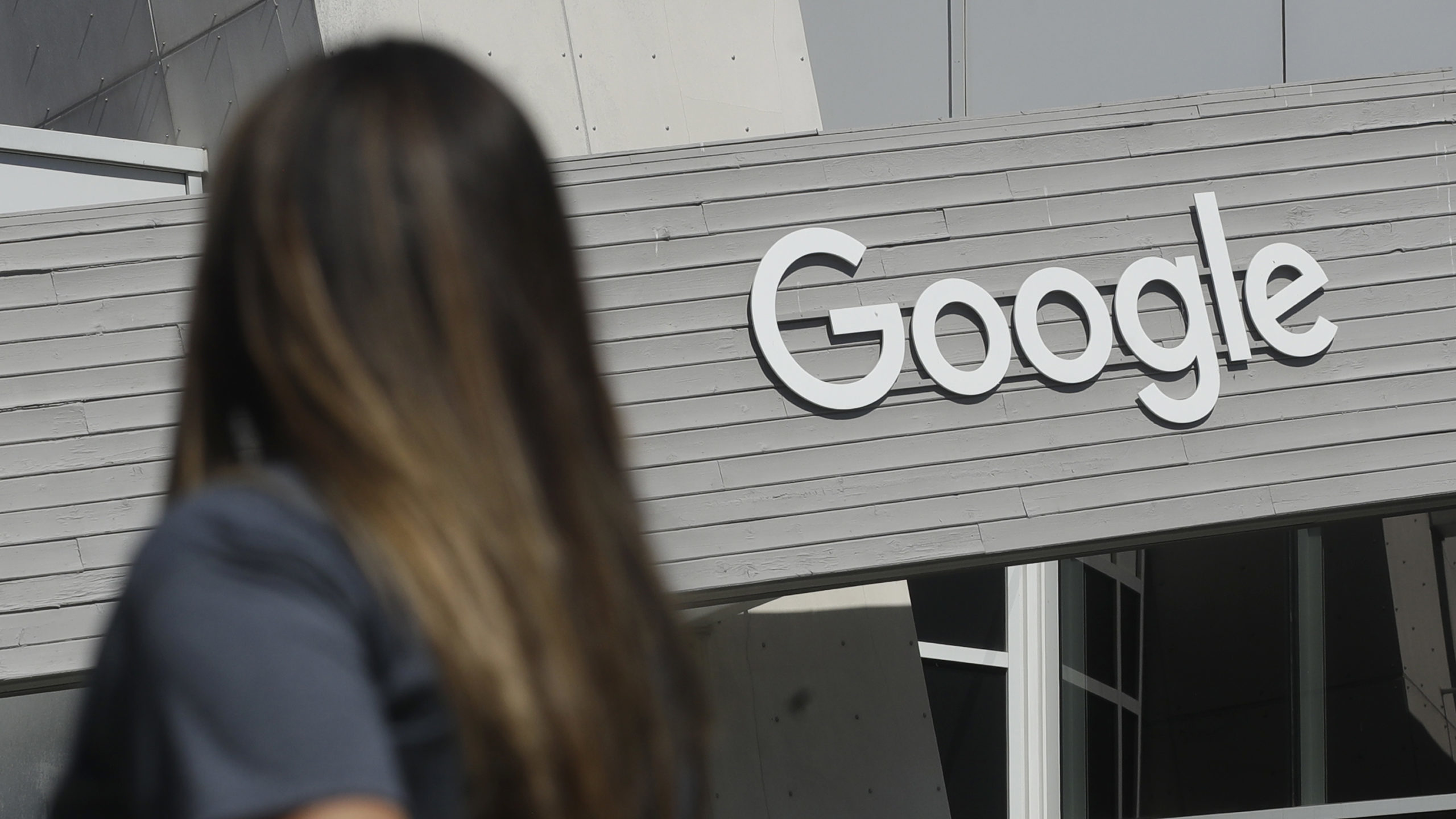 Woman walks past Google sign, which brought economic activity to Utah....
