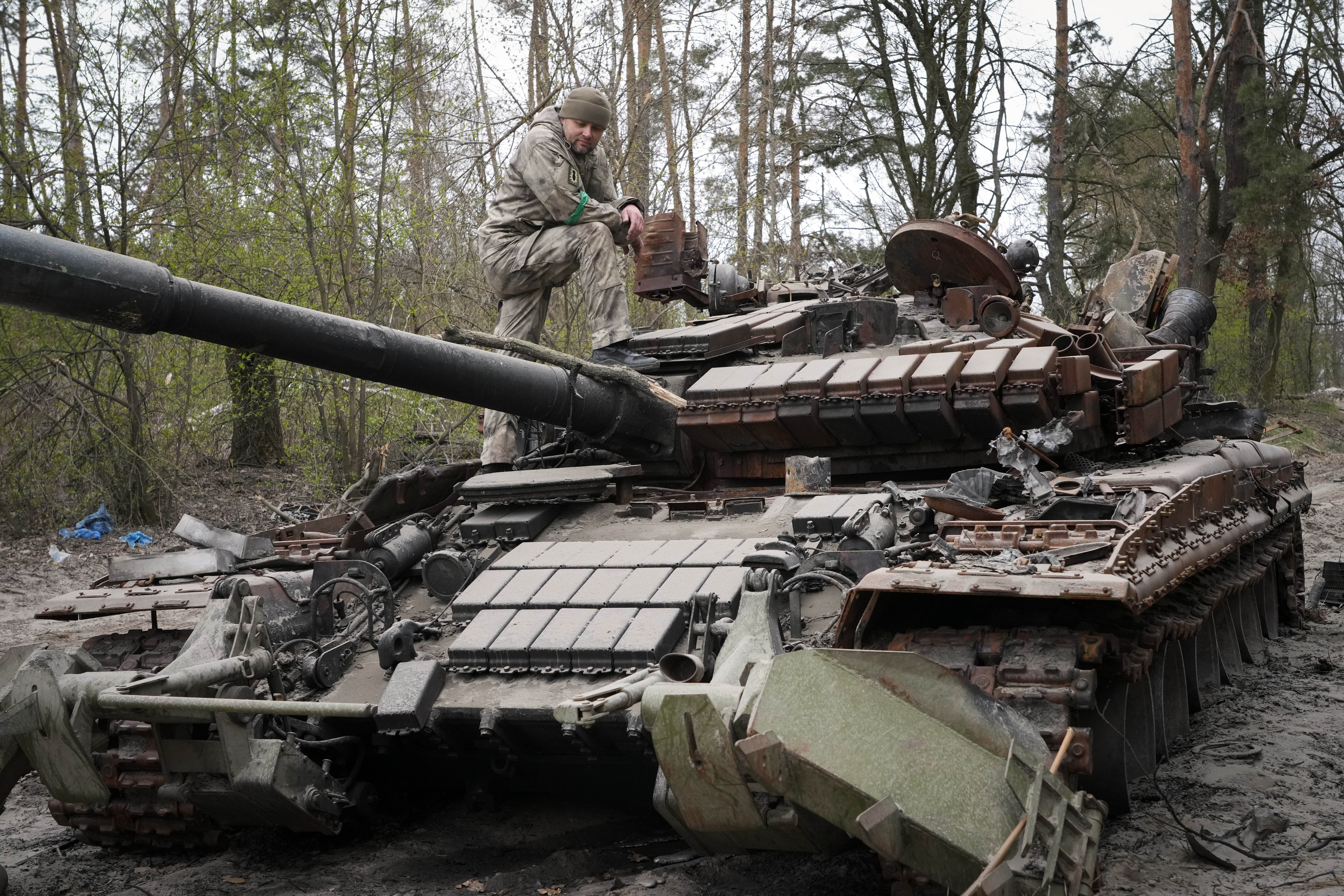 A Ukrainian soldier inspects a Russian tank after recent battles at the village of Moshchun close t...