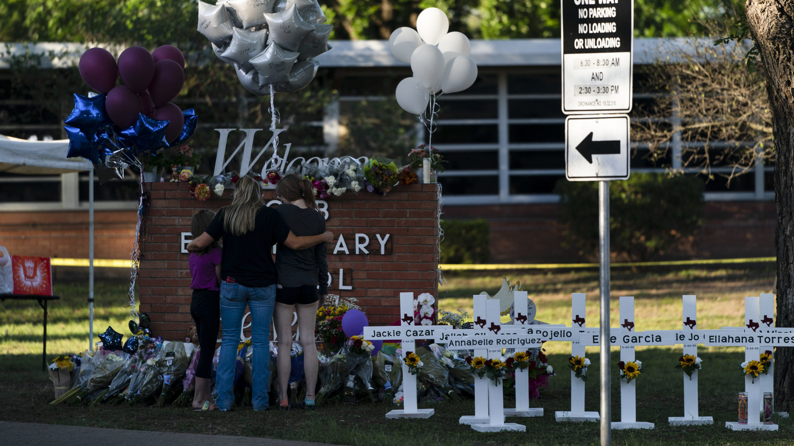 A family pays their respects next to crosses bearing the names of Tuesday's shooting victims at Rob...