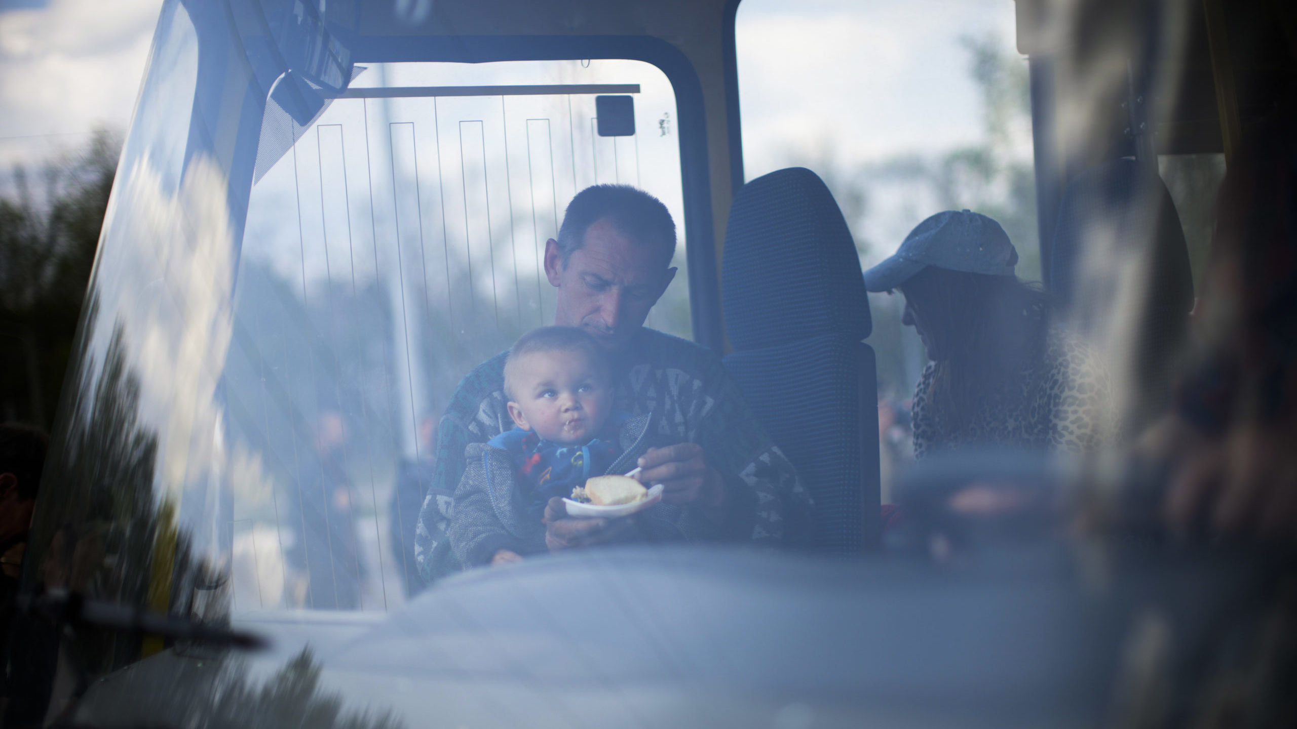 A man feeds a child as they arrive by bus at a reception center for displaced people in Zaporizhzhi...
