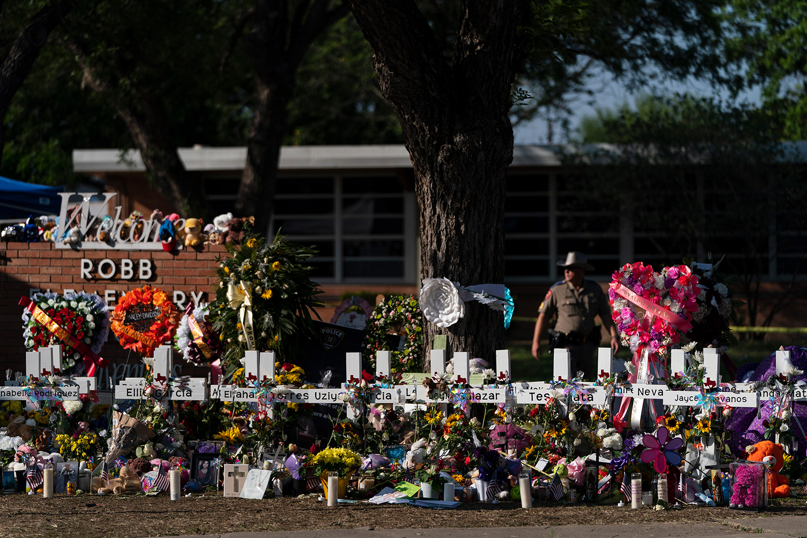 FILE - Flowers and candles are placed around crosses at a memorial outside Robb Elementary School t...