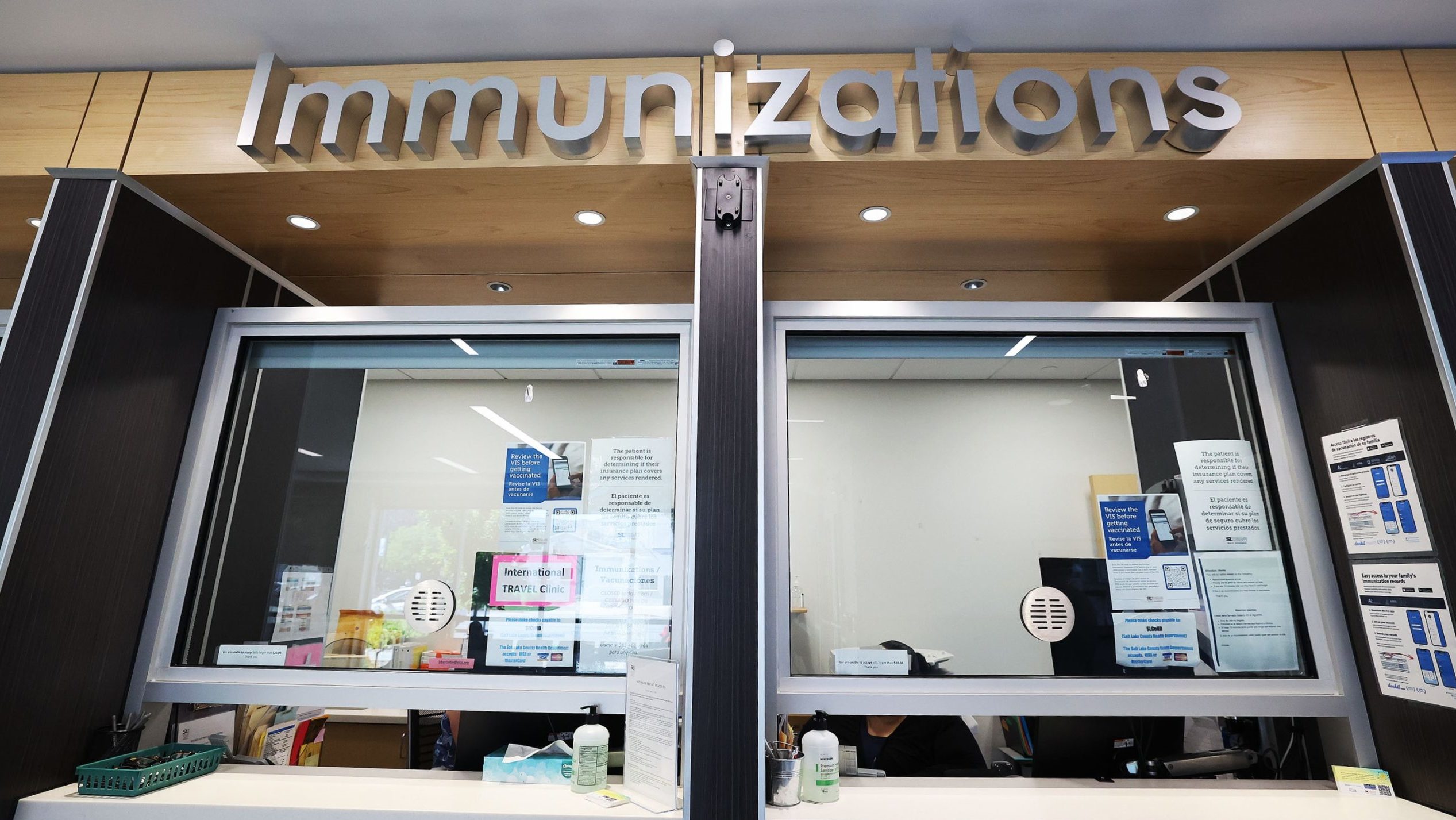 A sign reading "immunizations" hangs over a desk. COVID-19 vaccines Utah...