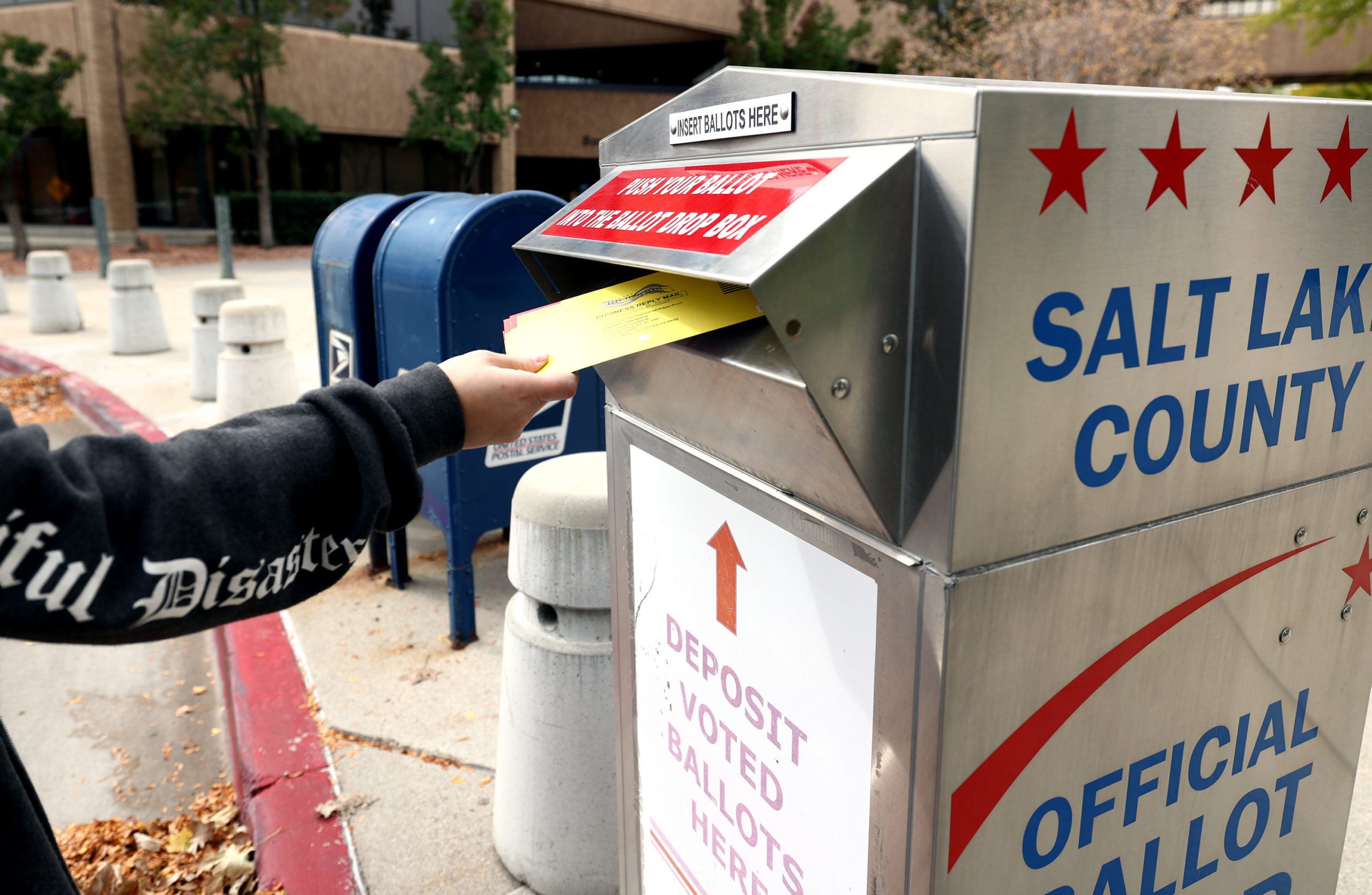 A voter drops a ballot into a box at the Salt Lake County Government Center in Salt Lake City on Mo...