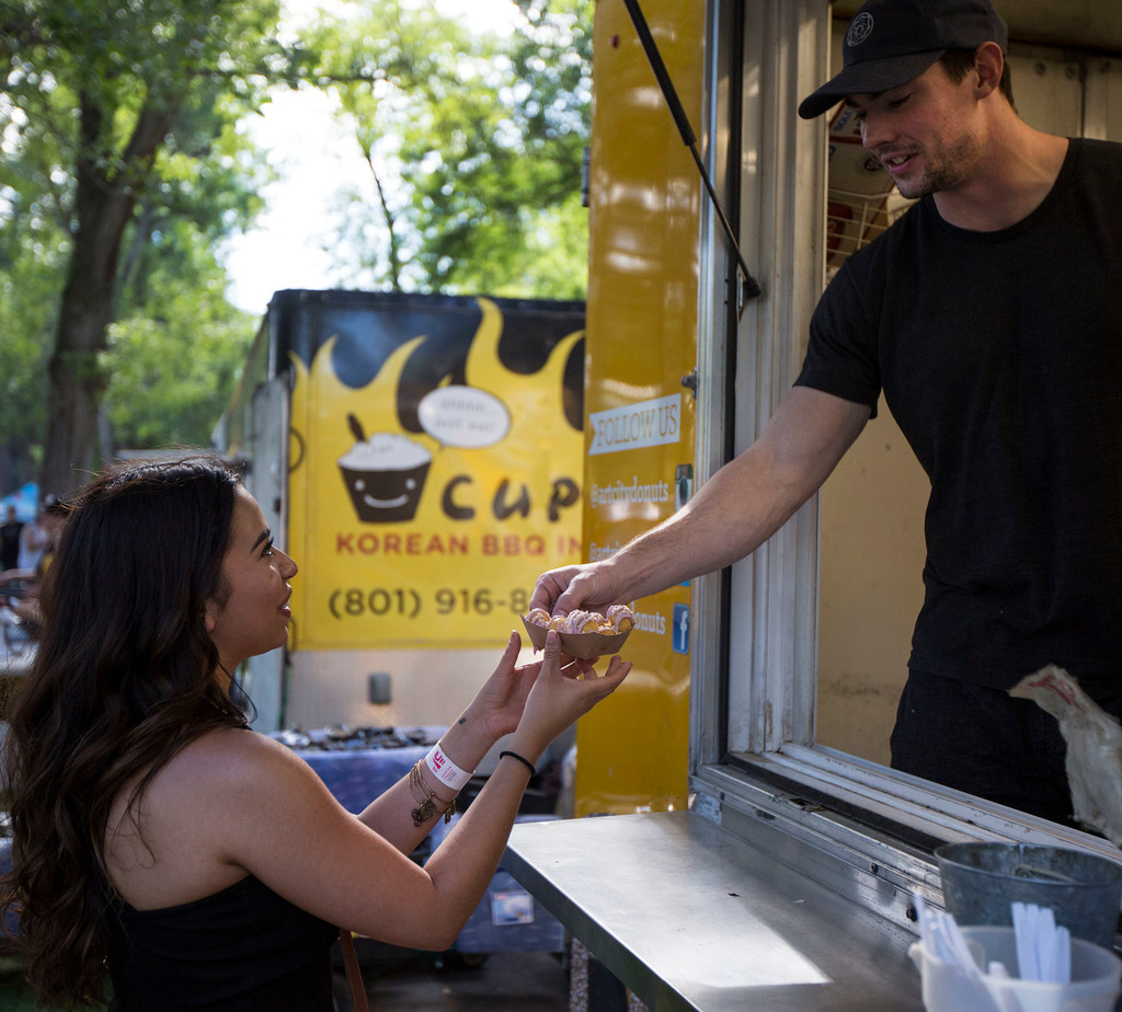 Art City Donut Truck's Conner Jensen, left, serves customers sugary desserts during the Food Truck ...