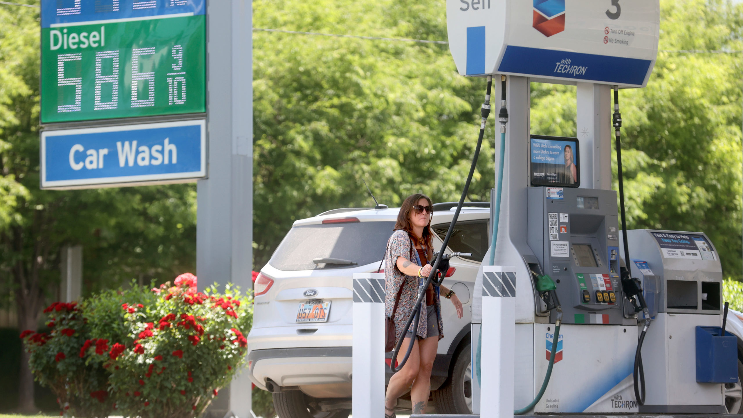 A woman pumps gas at a gas station....
