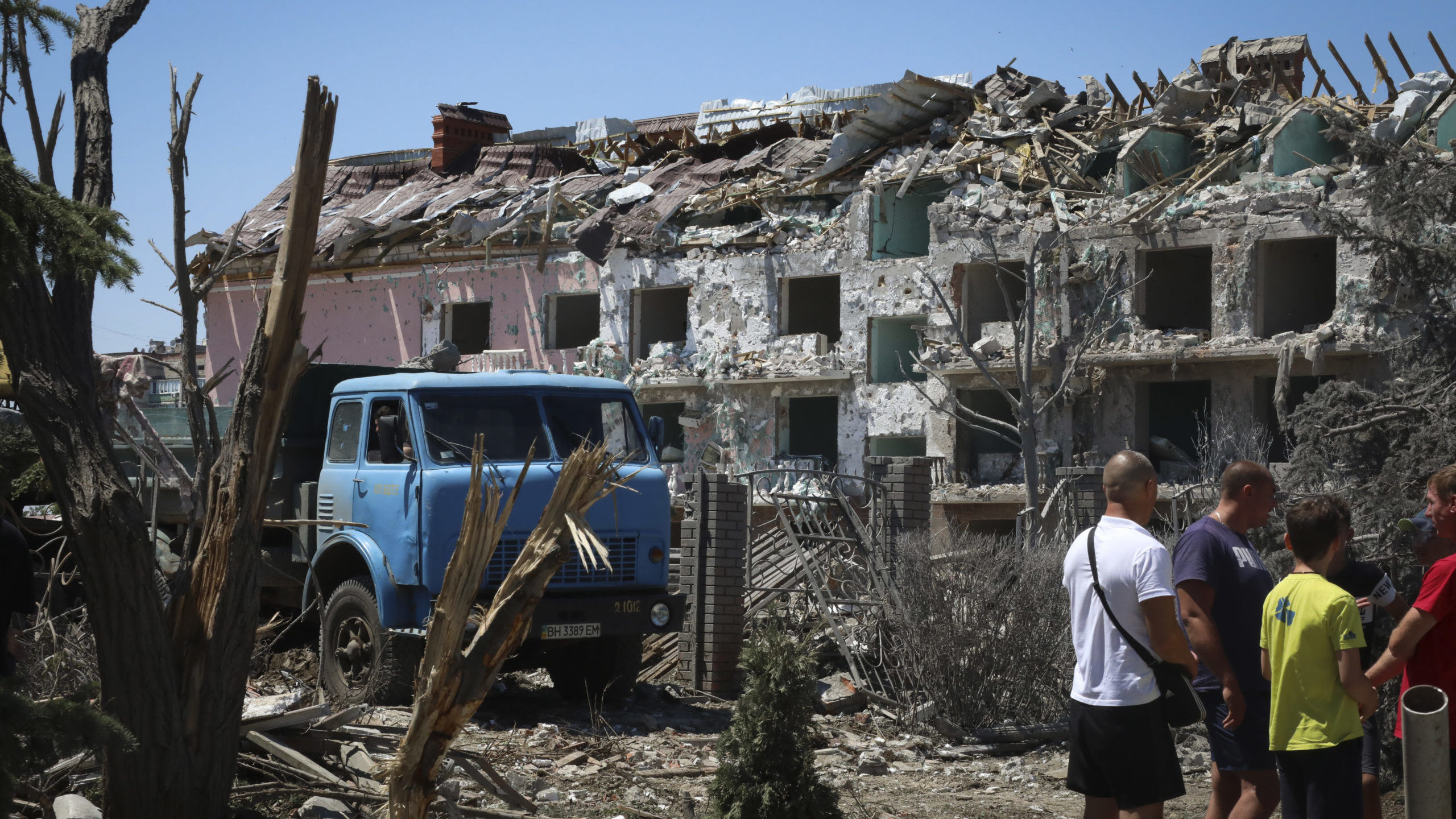 Residents stand in front of building destroyed by missiles in Ukraine...