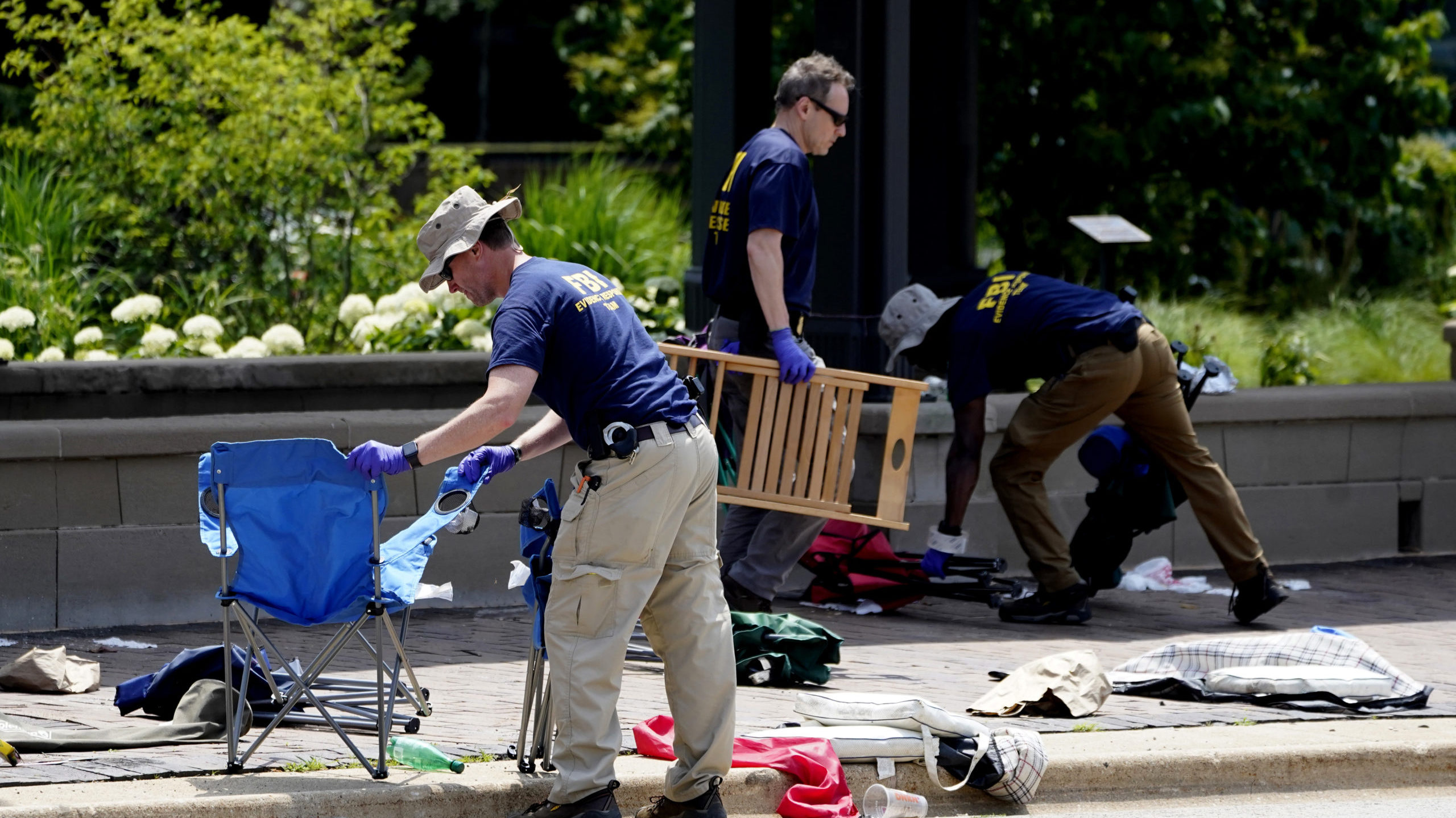 Two members of the FBI move items from the scene at the Highland Park shooting...