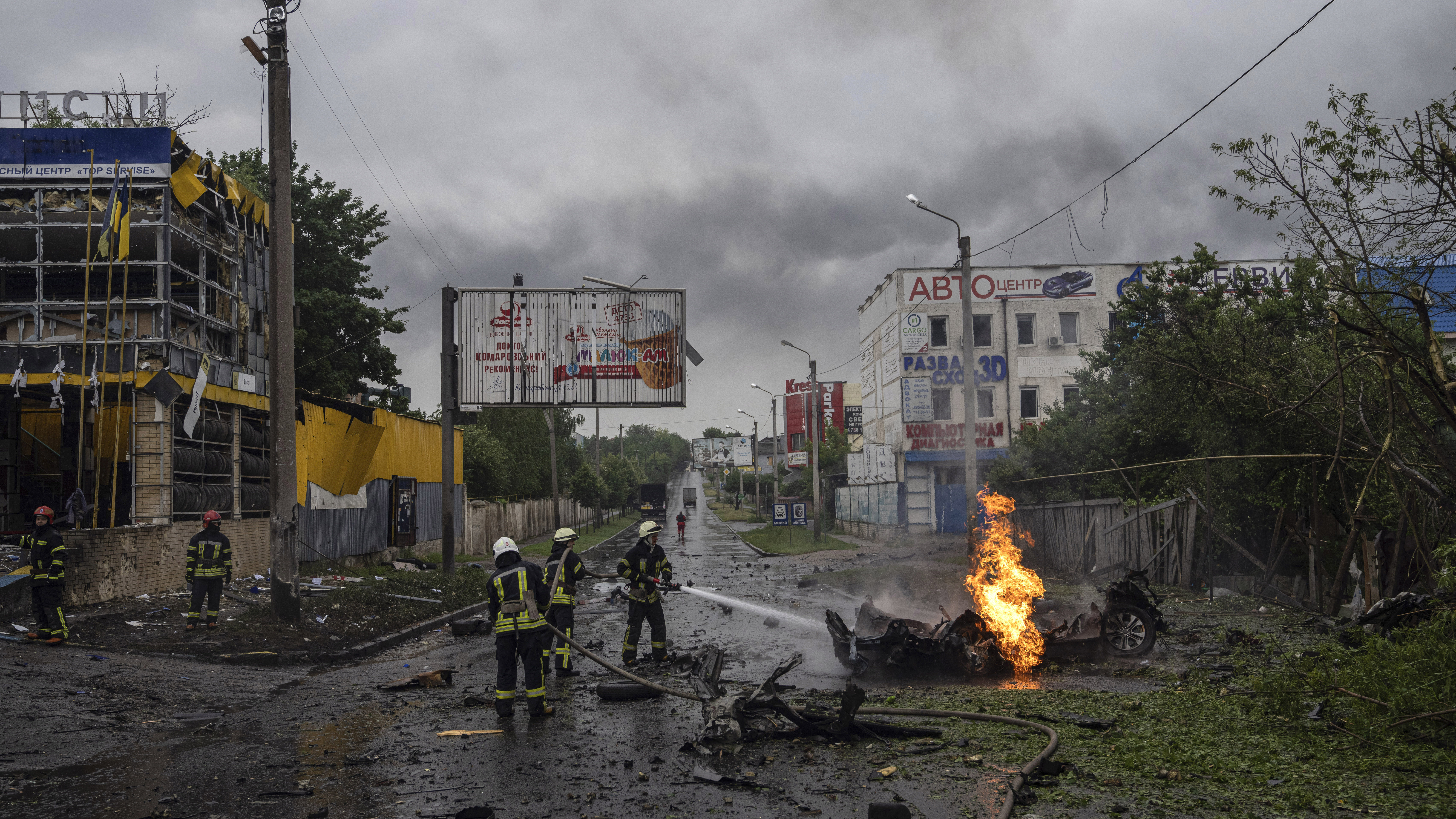 Rescue workers put out the fire of a destroyed car after a Russian attack in a residential neighbor...