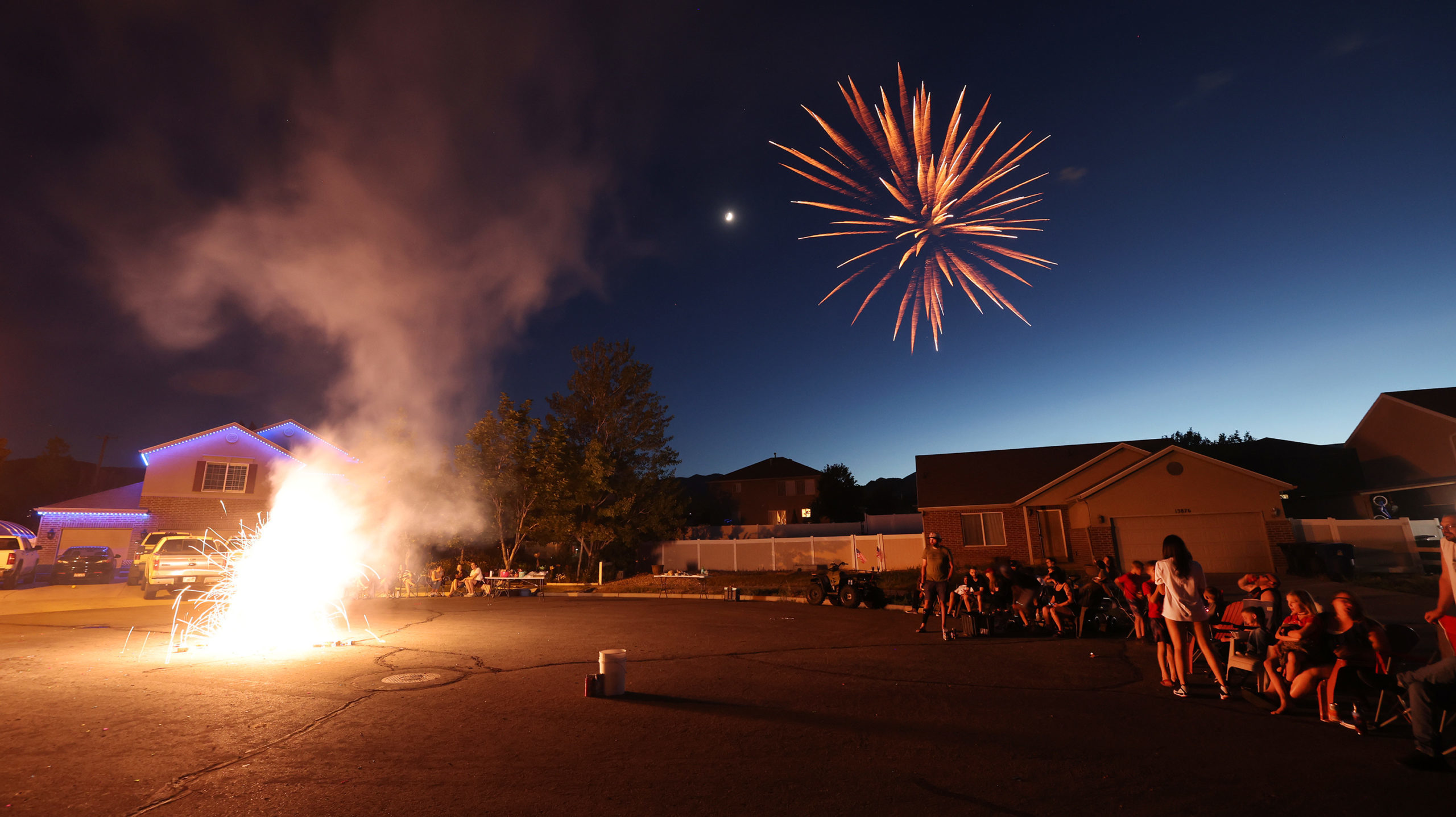 Fireworks go off on a street as residents watch. Will people light fireworks for Pioneer Day?...