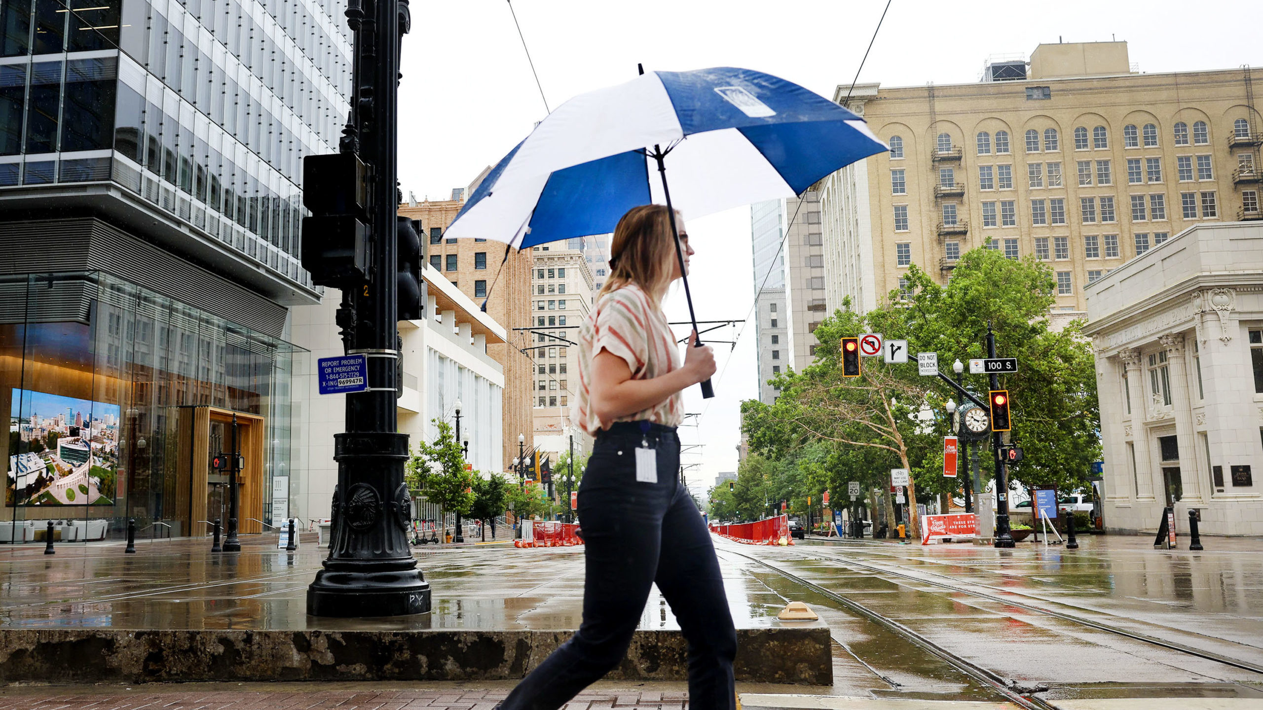 A woman crosses the street holding an umbrella up. Did the recent rain help the drought in Utah?...