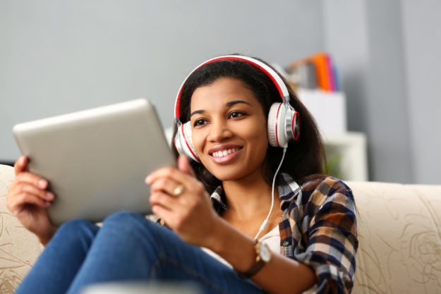 Young Black female watching a tablet with headphones in