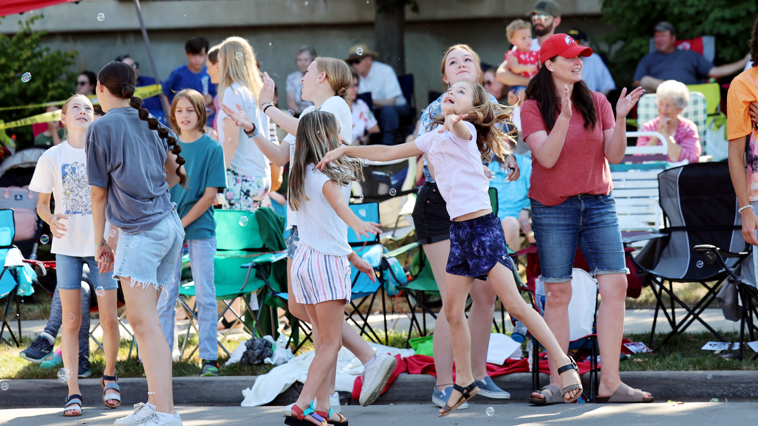 FILE: Kids jump and try to hit bubbles as they watch the Bountiful Handcart Days parade on Saturday...