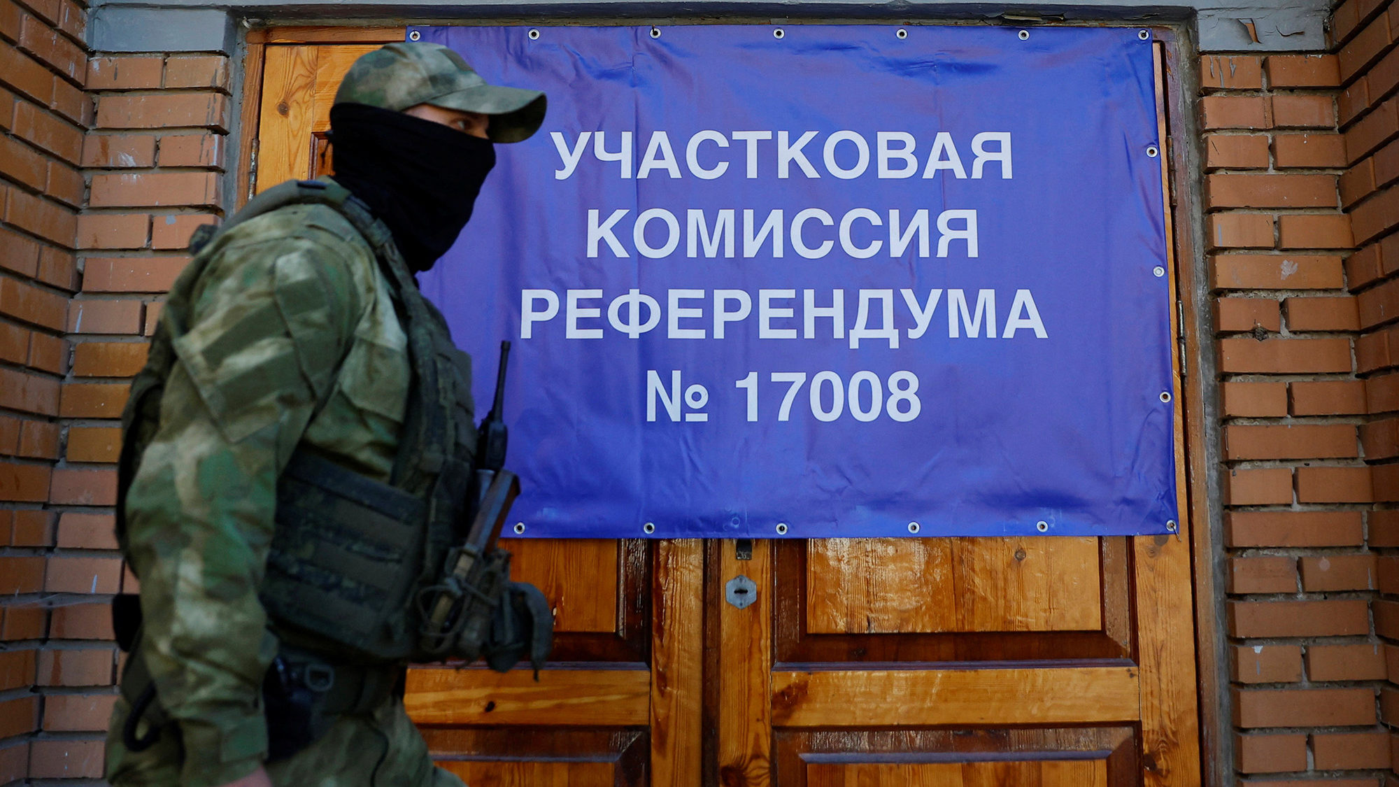 A service member of the self-proclaimed Donetsk People's Republic walks past a banner on the doors ...