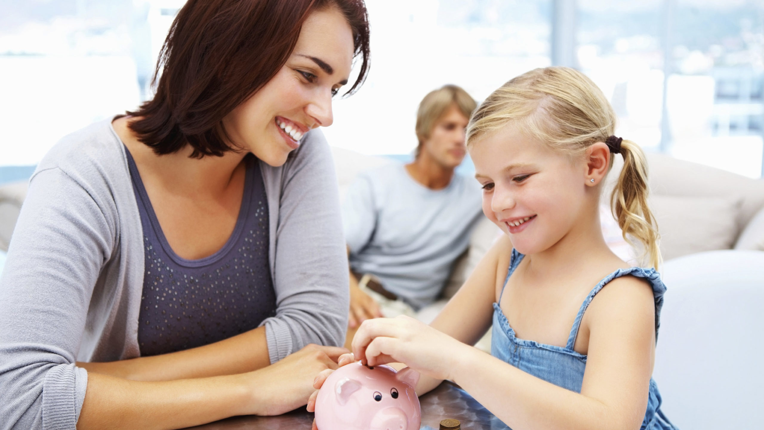 Mom and daughter with piggy bank. Parents can have a big role in the financial education of their k...