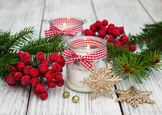 christmas decorations candles in glass jars with fir on a old wooden table...