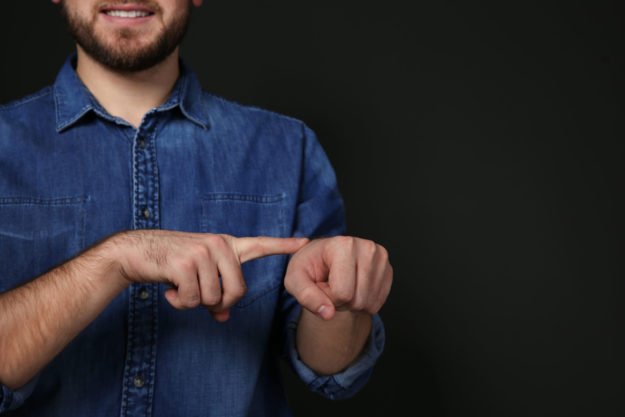 Man showing word TIME in sign language on black background, spac