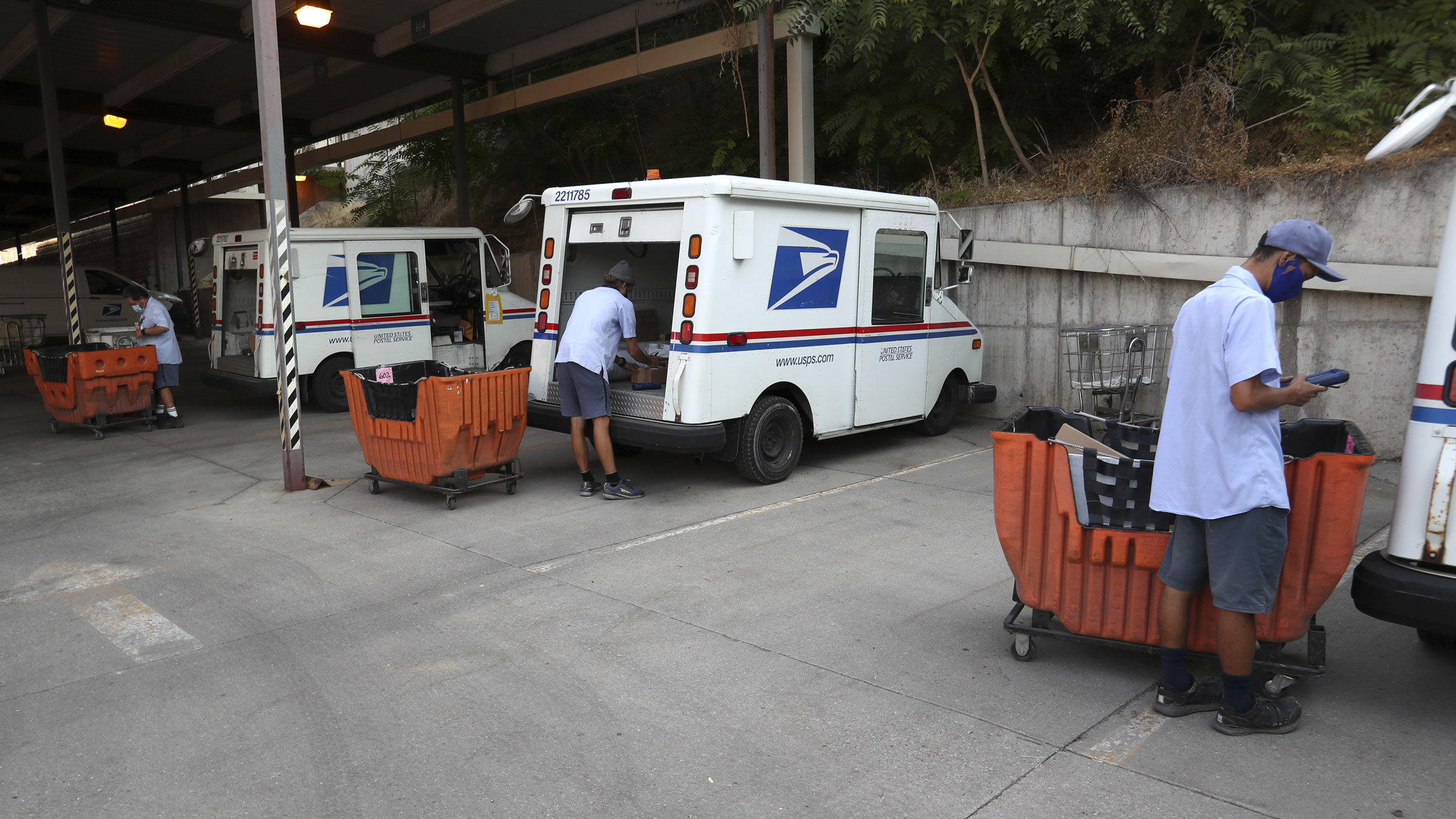 USPS mailmen and cars shown, a mailman was the victim of a robbery in august...