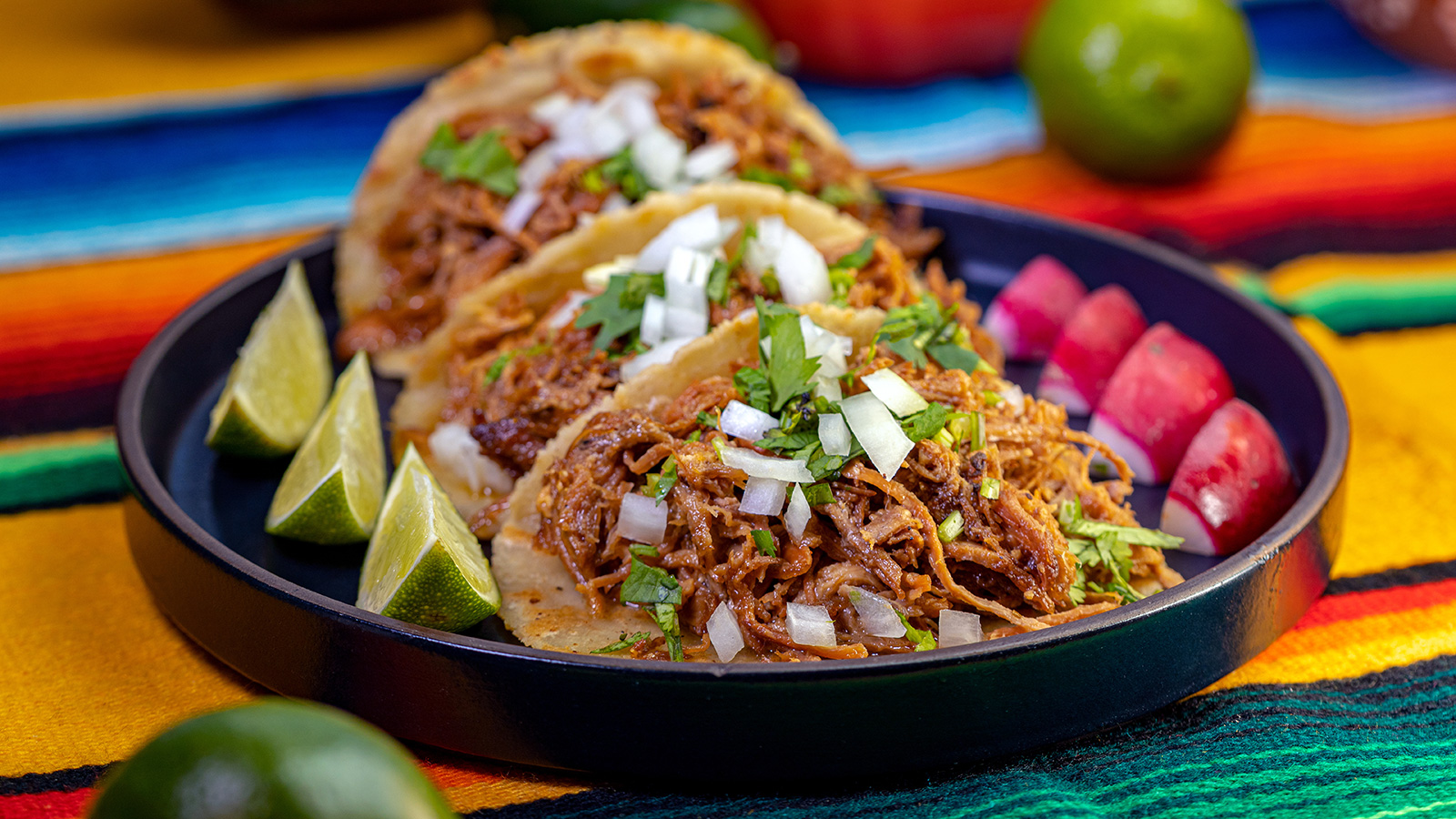 Three Fresh Carnitas Tacos on a plate wth lime and radish...