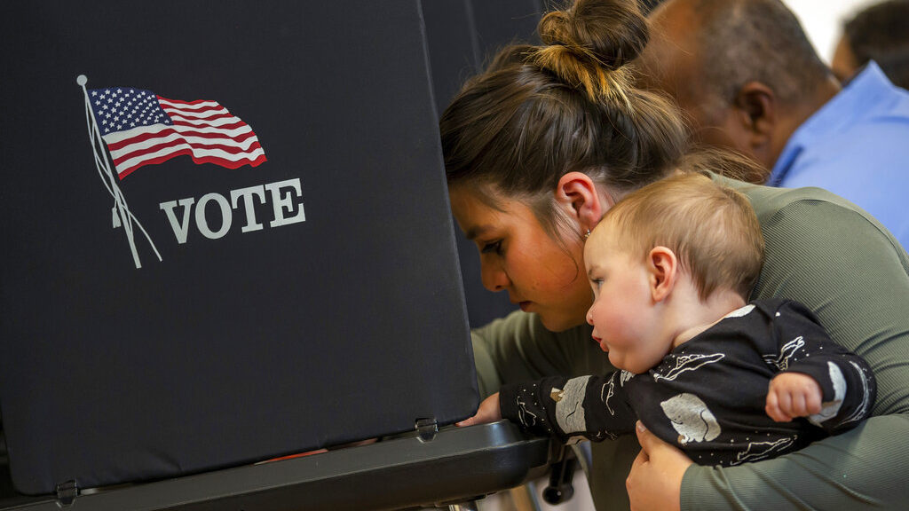 Miranda Padilla holds her 11-month-old son Grayson Sanchez while marking her ballot at a polling ce...