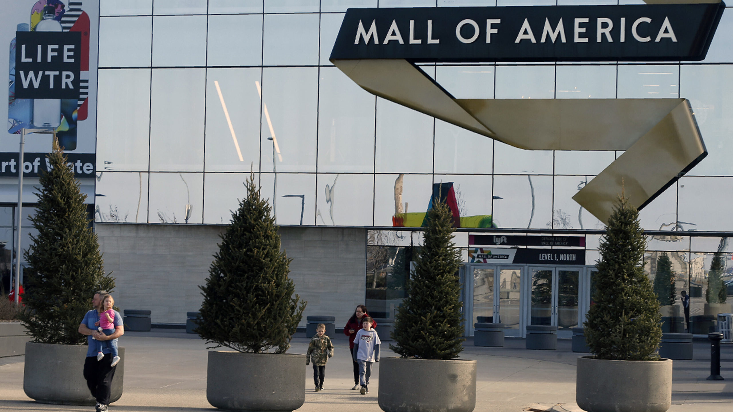FILE - Shoppers, visitors and employees exit the Mall of America on March 17, 2020 as the mall in B...