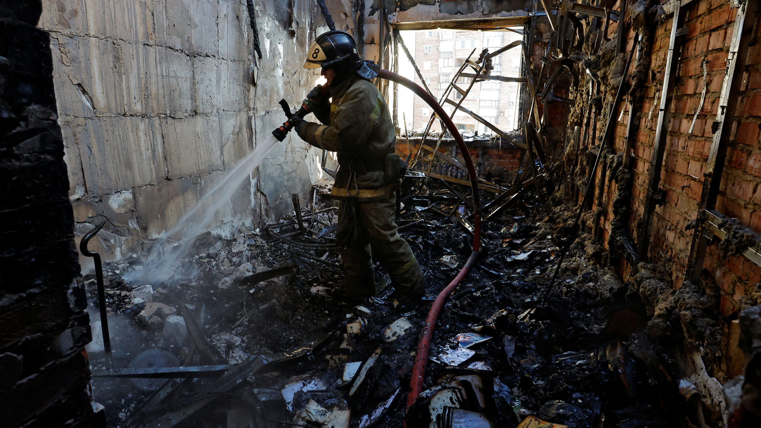 A firefighter works inside a destroyed apartment of a residential building hit by shelling in the c...