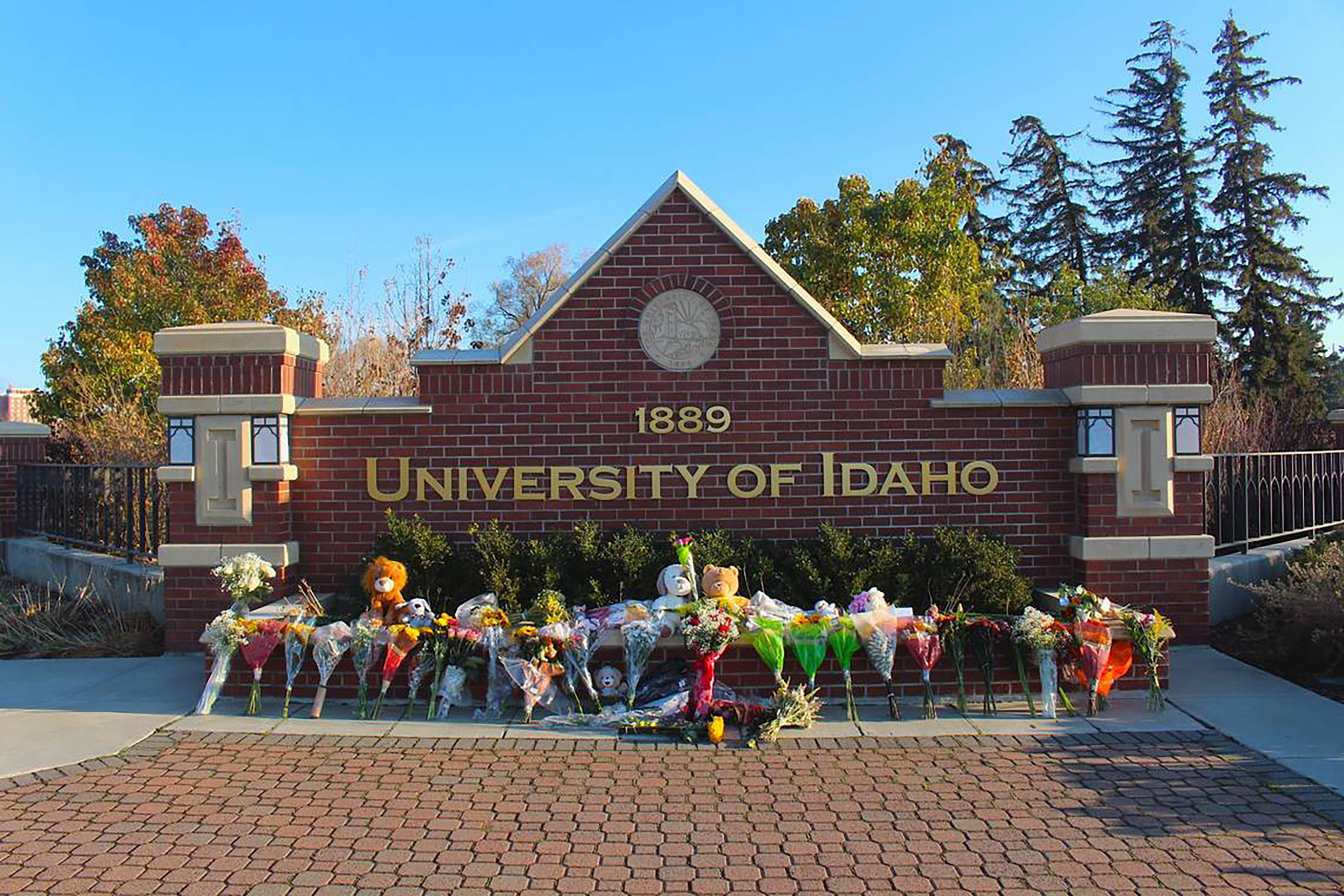 Flowers and stuffed animals are lined up outside a sign along Pullman Road in Moscow, Idaho, to pay...