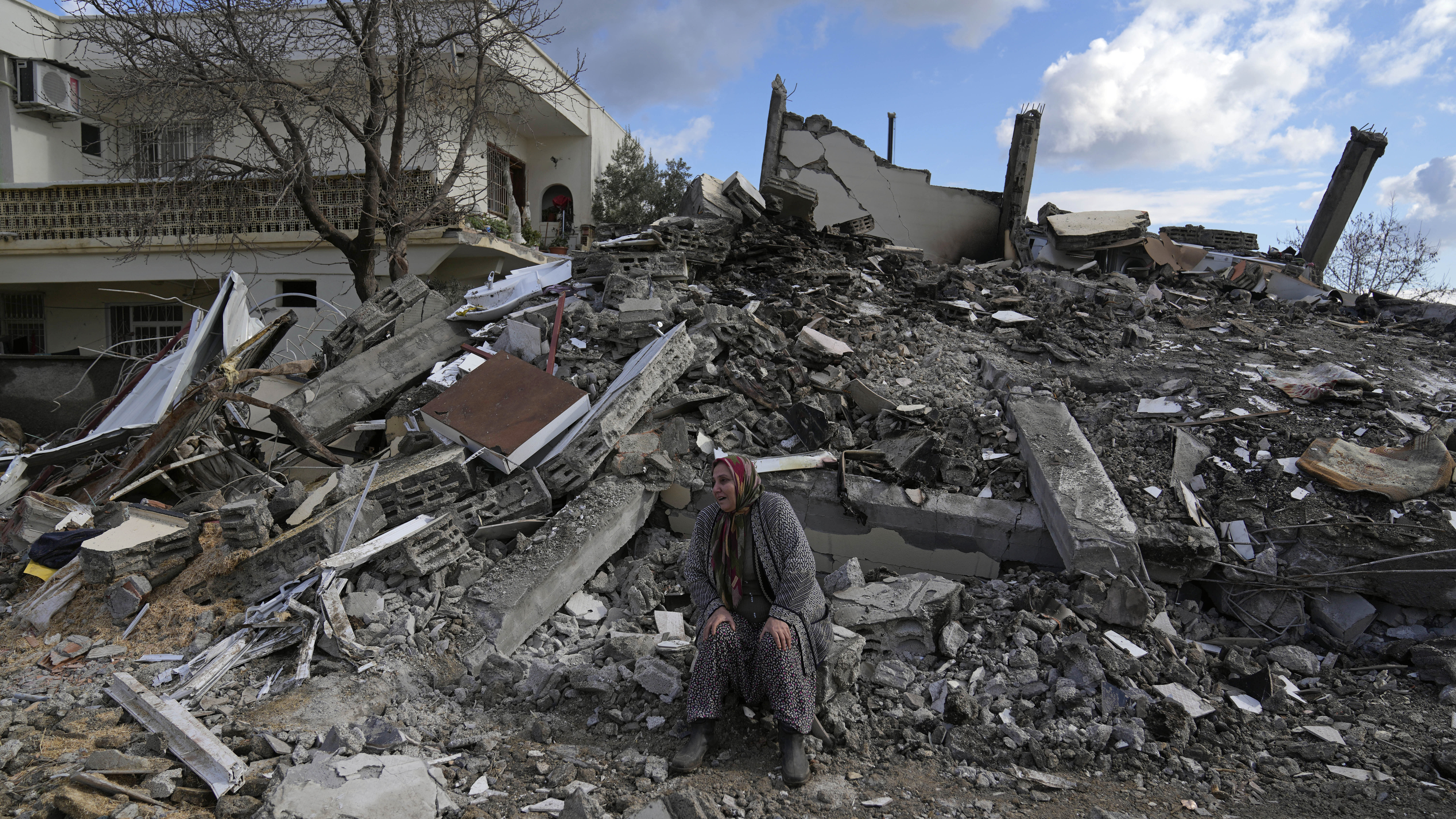 A woman sits on the rubble as emergency rescue teams search for people under the remains of destroy...