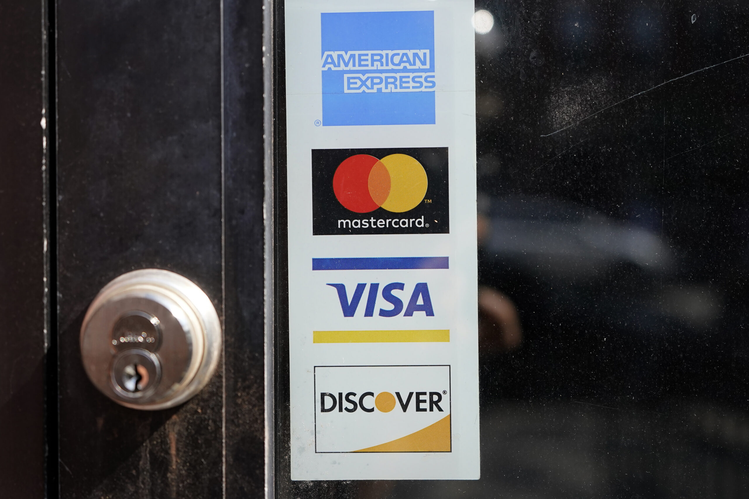 File - Credit card logos are displayed on a business's door, Monday, July 5, 2021, in Cambridge, Ma...